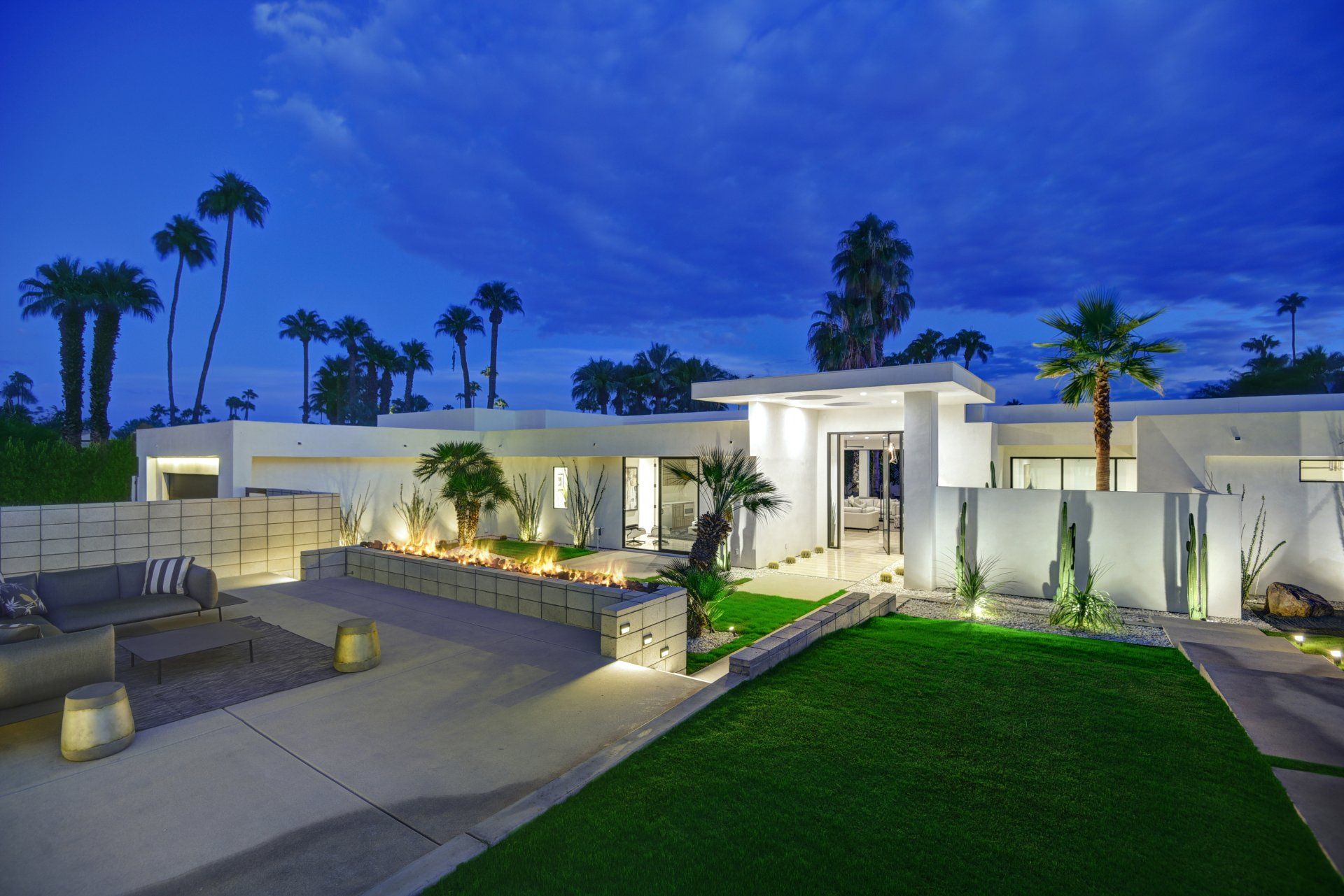 A large white house with palm trees in the background at night.