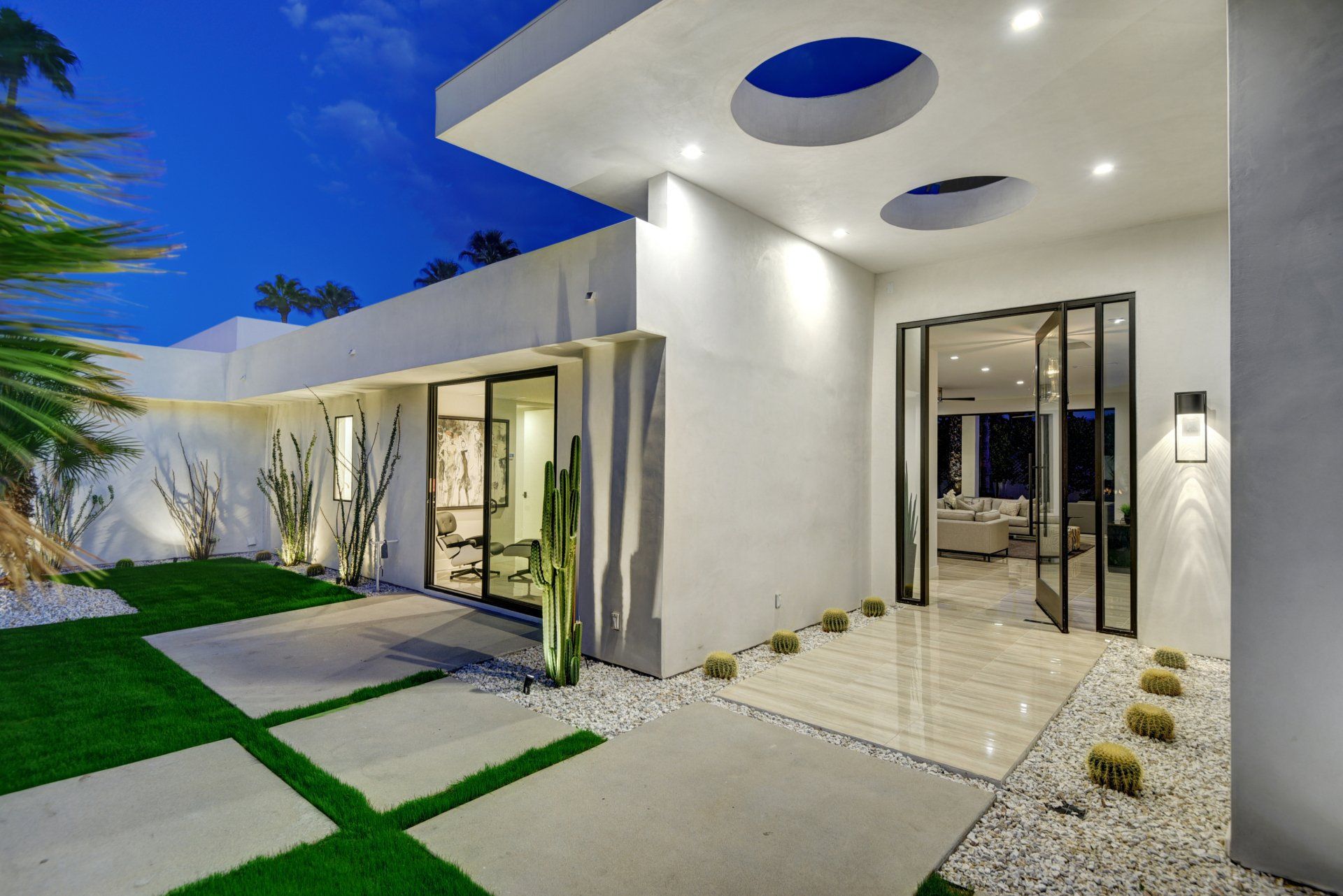 A modern white house with a patio and a sliding glass door.