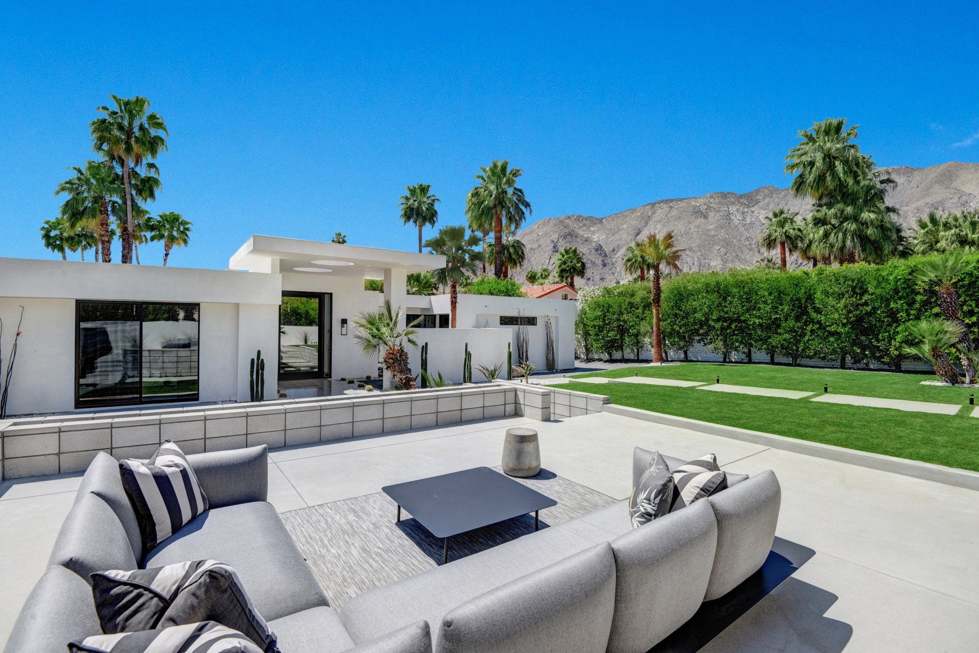 A patio with a couch and a coffee table in front of a house.