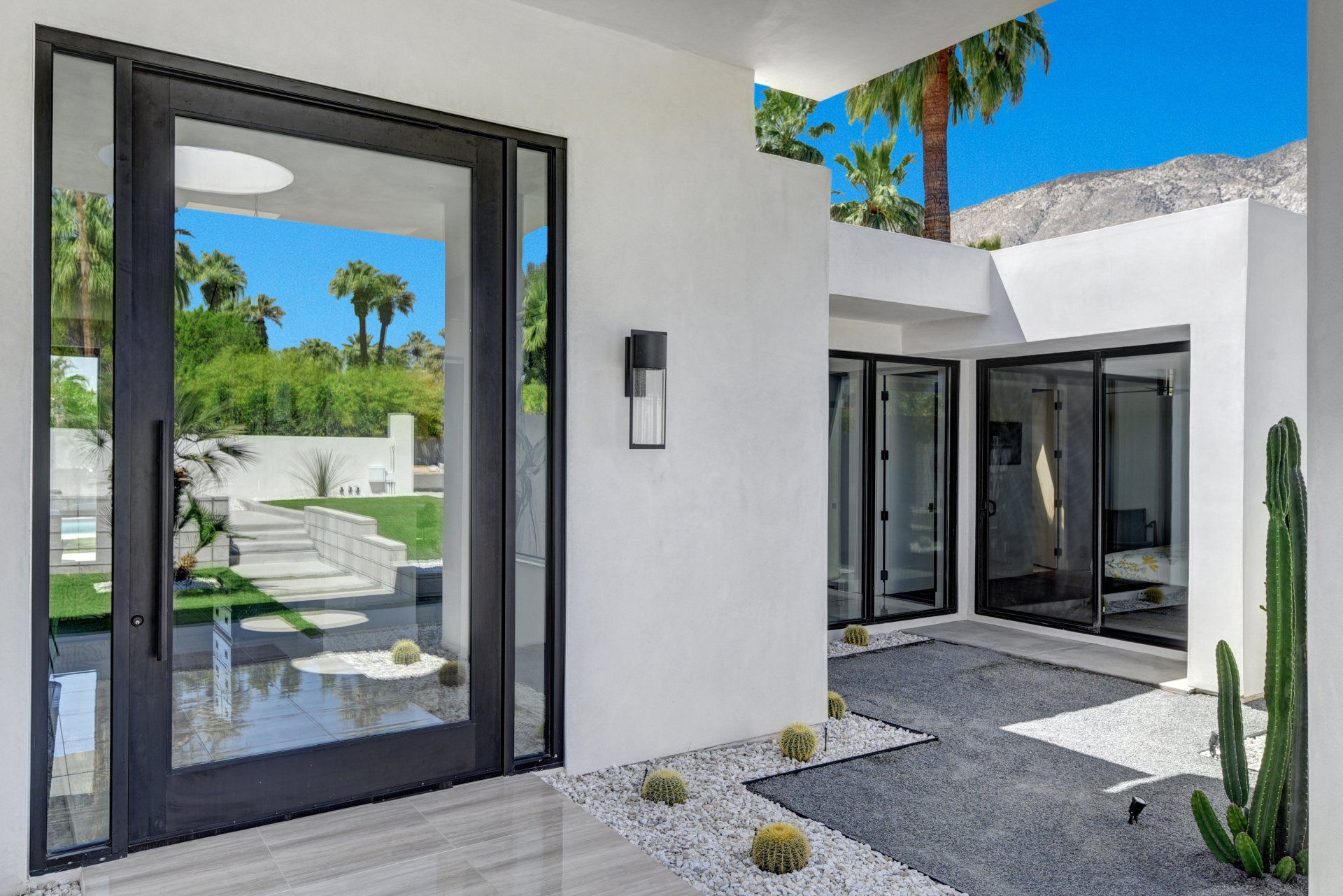 A white house with a black door and a cactus in front of it.