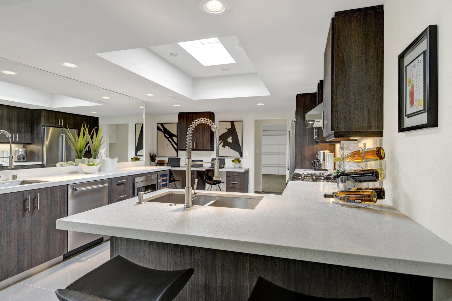 A kitchen with two sinks , a bottle holder , and a skylight.