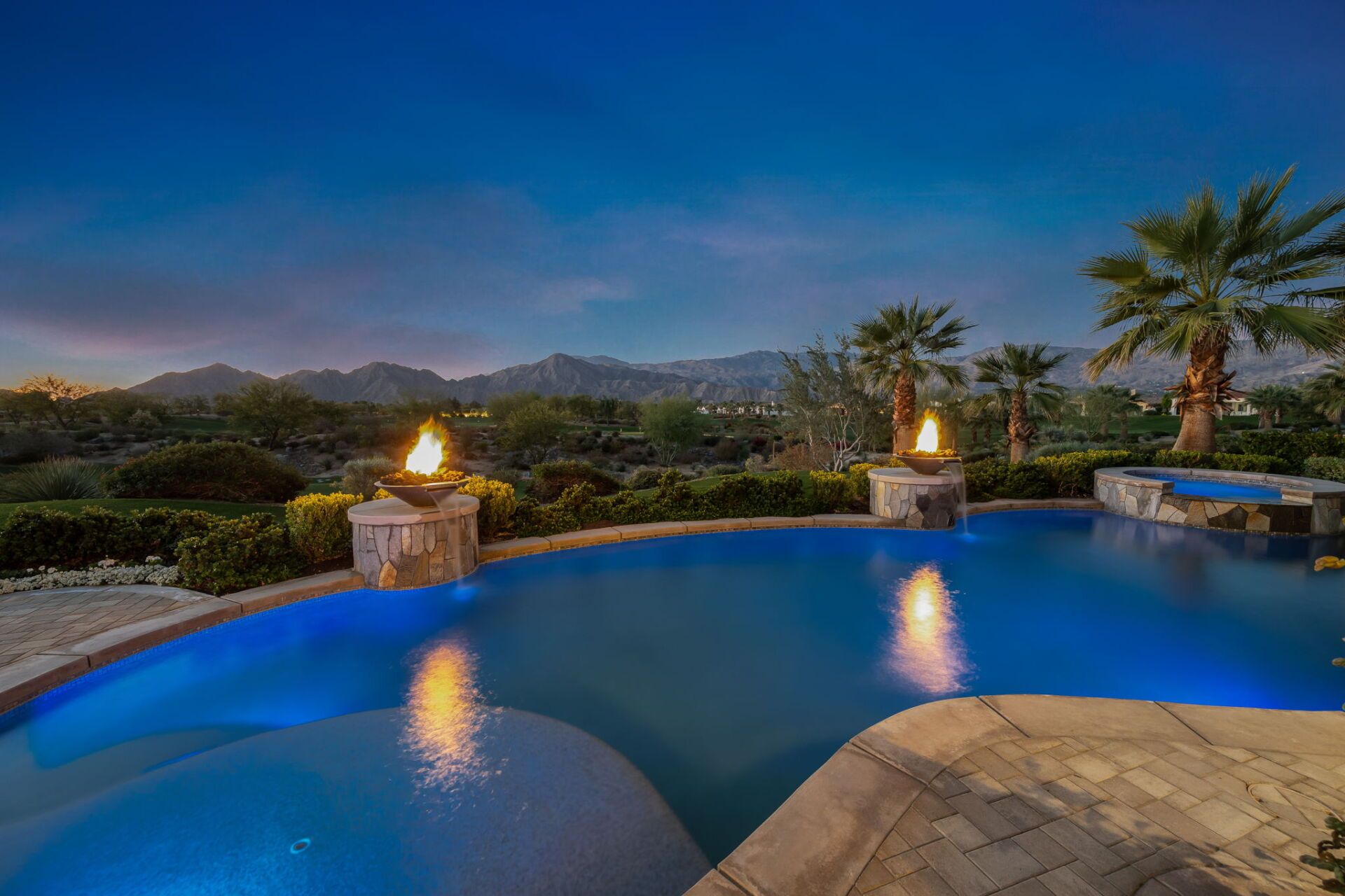 There is a large swimming pool with a fire pit in the middle of it.