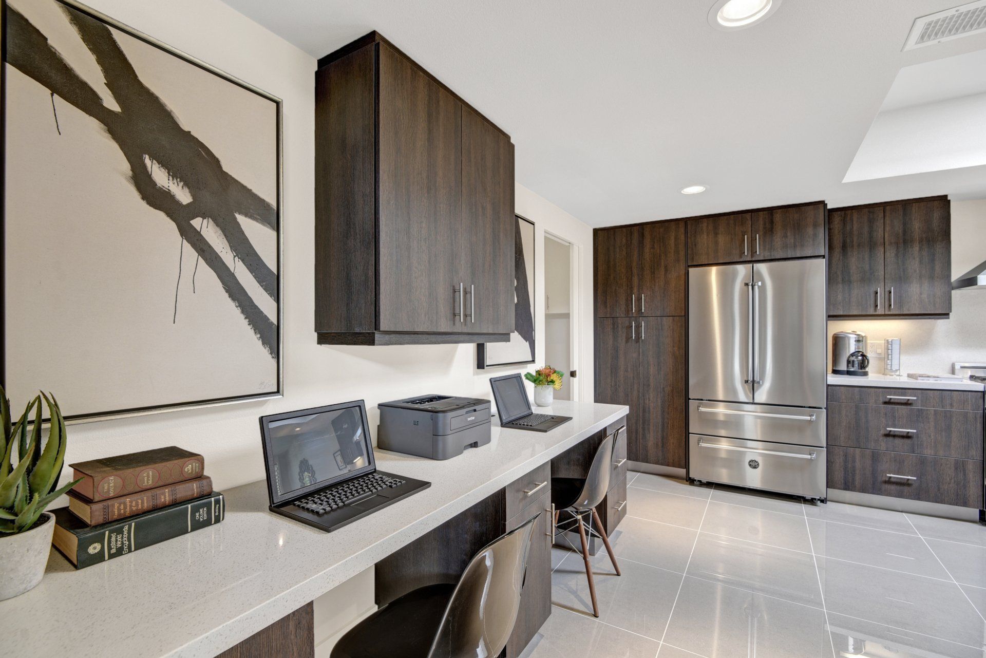 A kitchen with a desk with two laptops and a printer on it