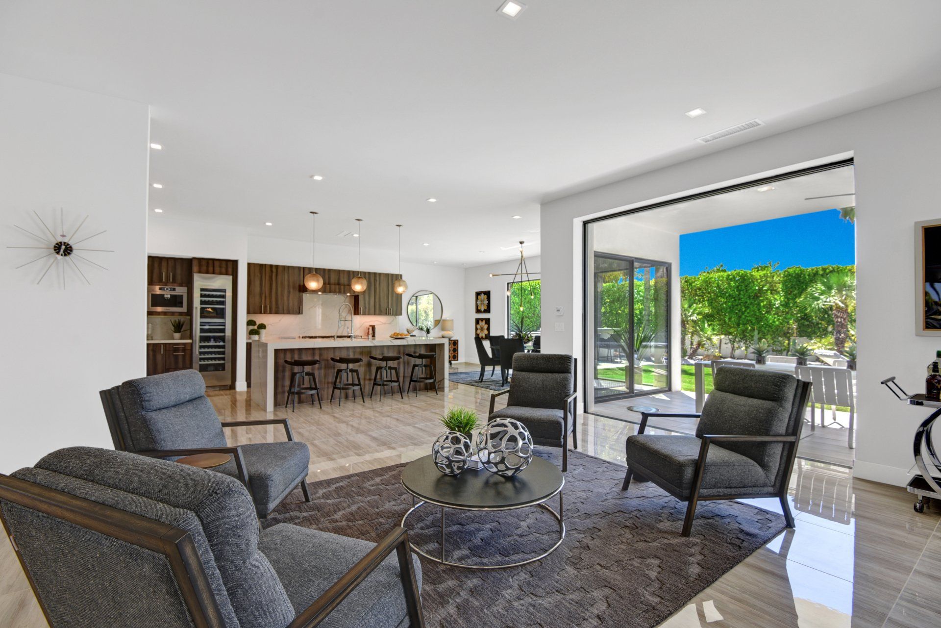 A living room with chairs , a coffee table , and a sliding glass door leading to a kitchen.