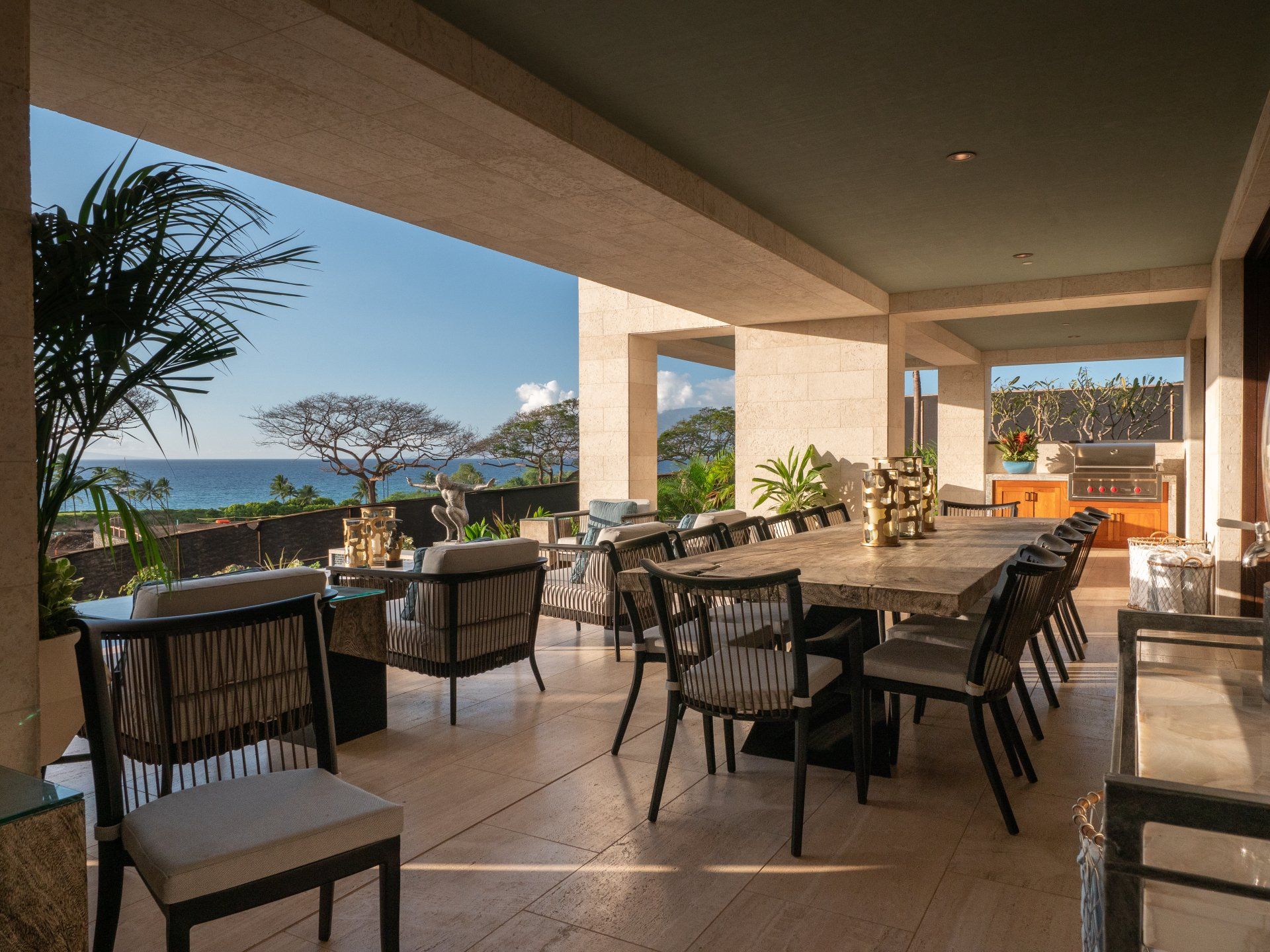 A dining room with a long table and chairs and a view of the ocean.