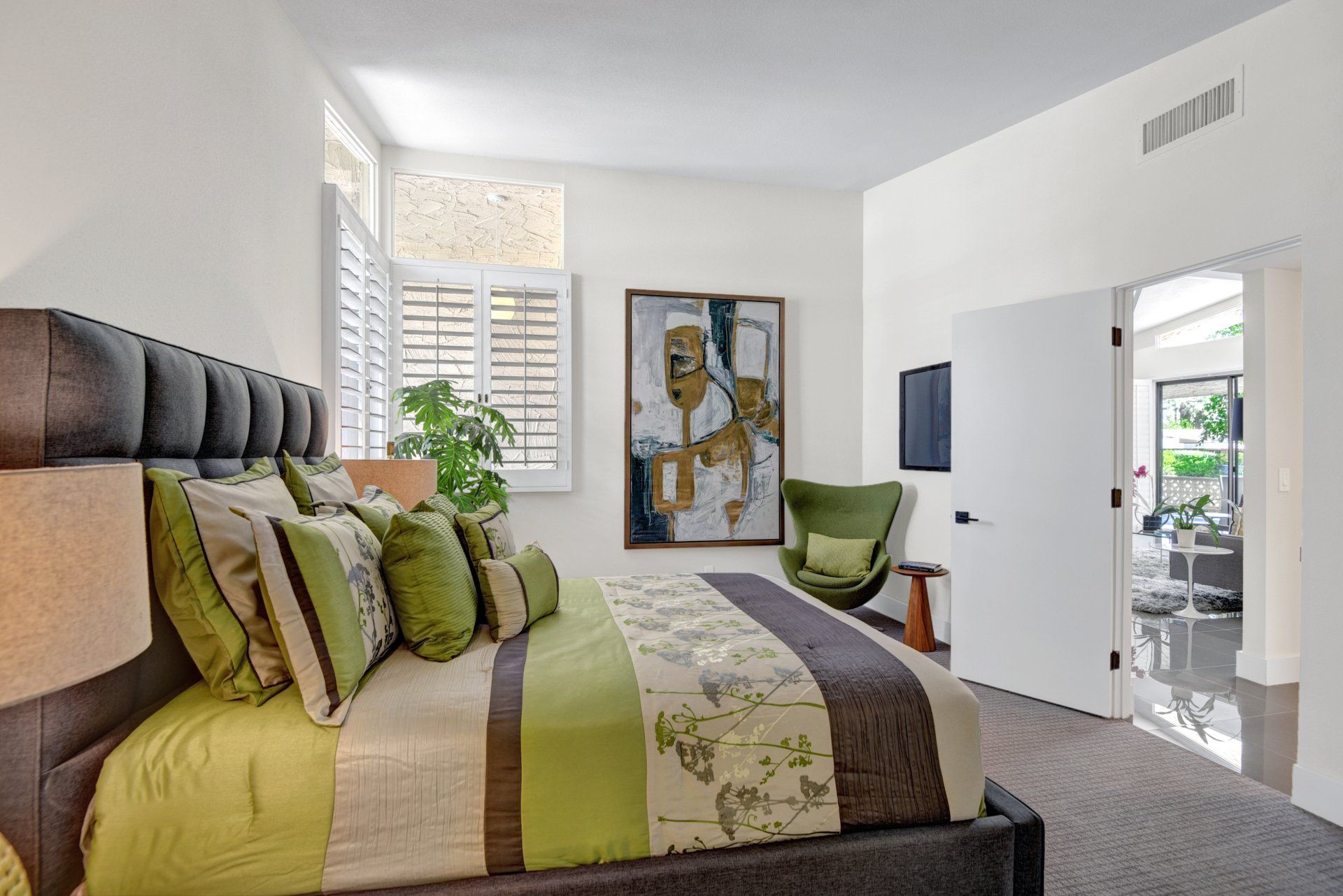 A bedroom with a large bed and a painting on the wall