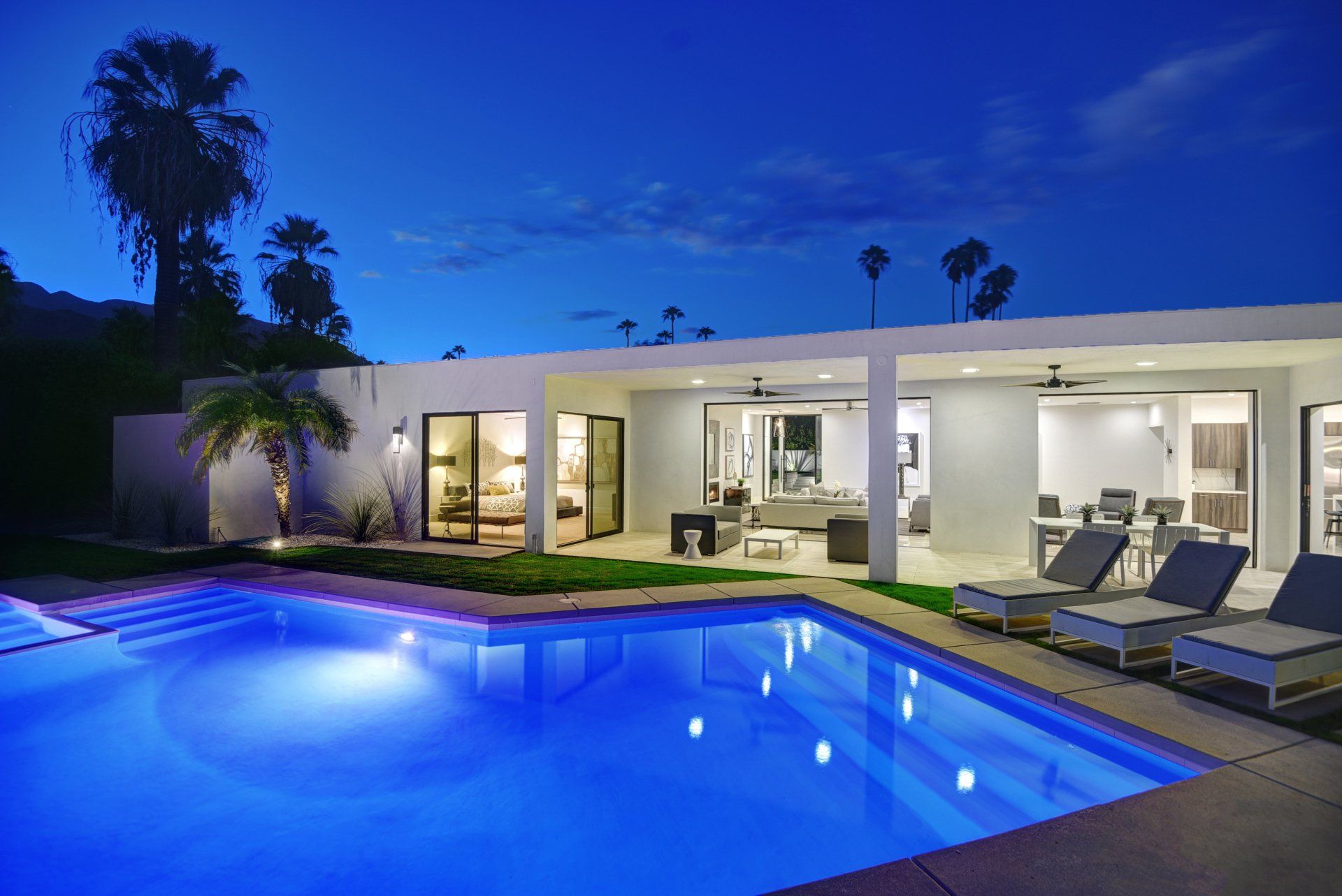 A large swimming pool in front of a house at night.