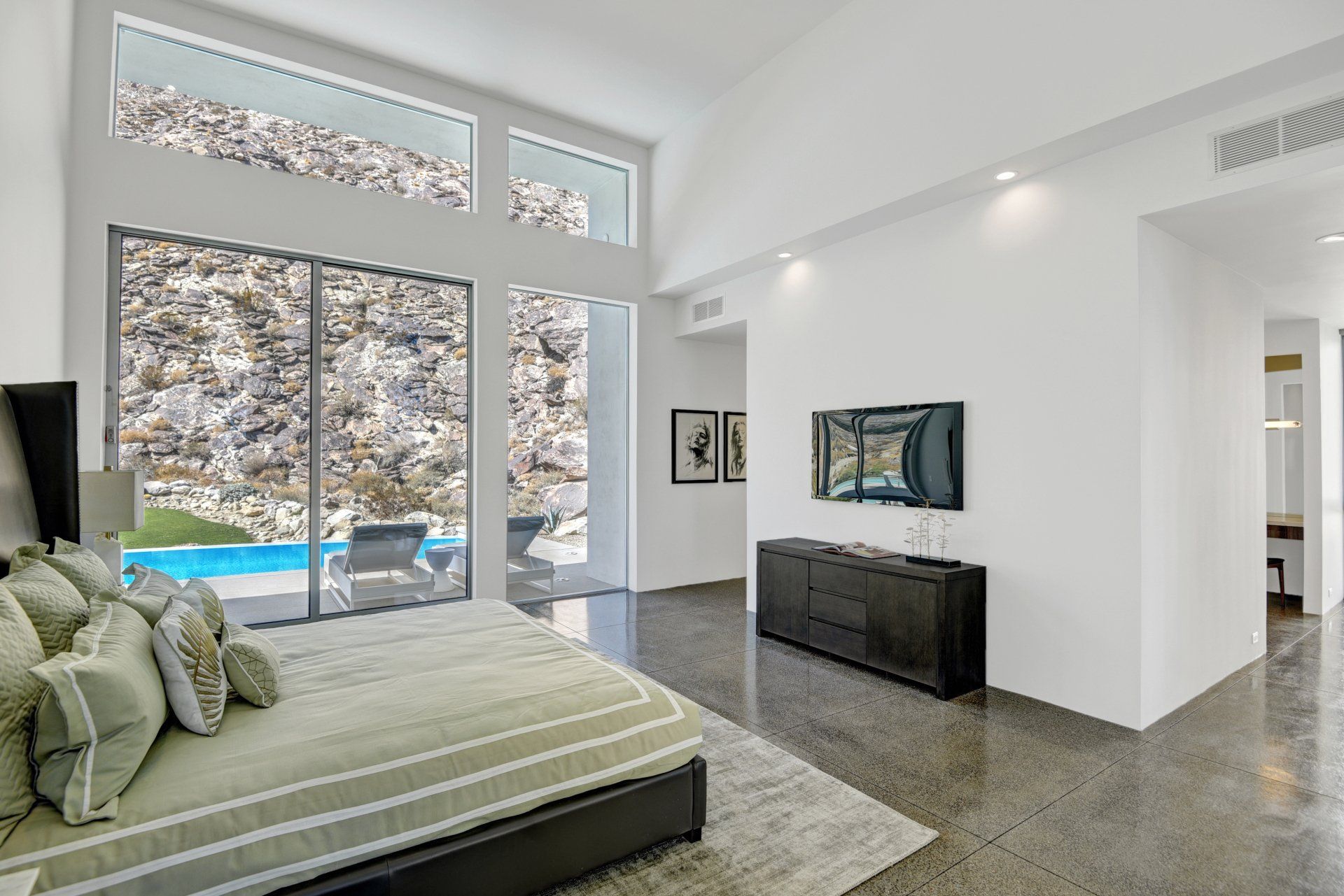 A bedroom with a large bed and a television on the wall.