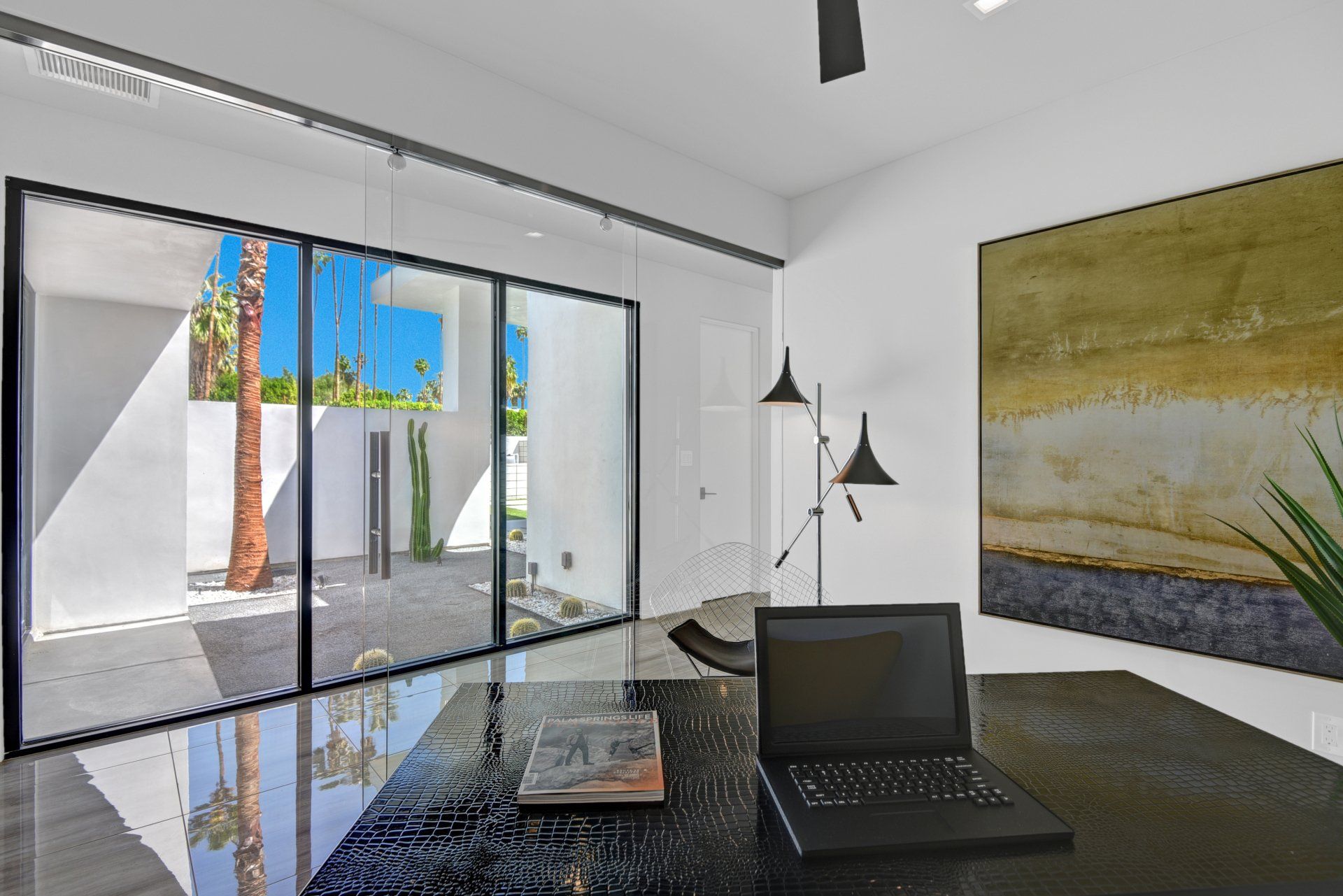 A laptop is sitting on a desk in a room with a lot of windows.