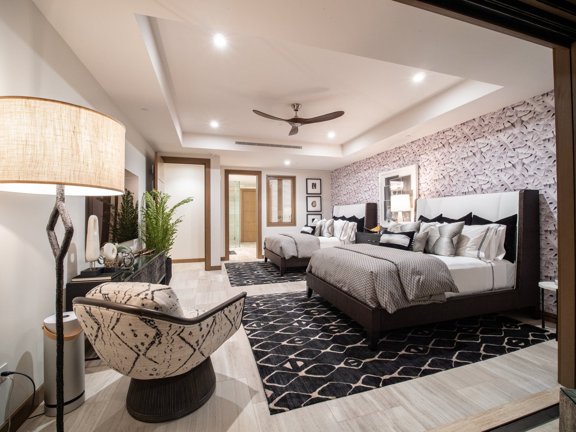 A bedroom with two beds , a chair , a lamp and a ceiling fan.