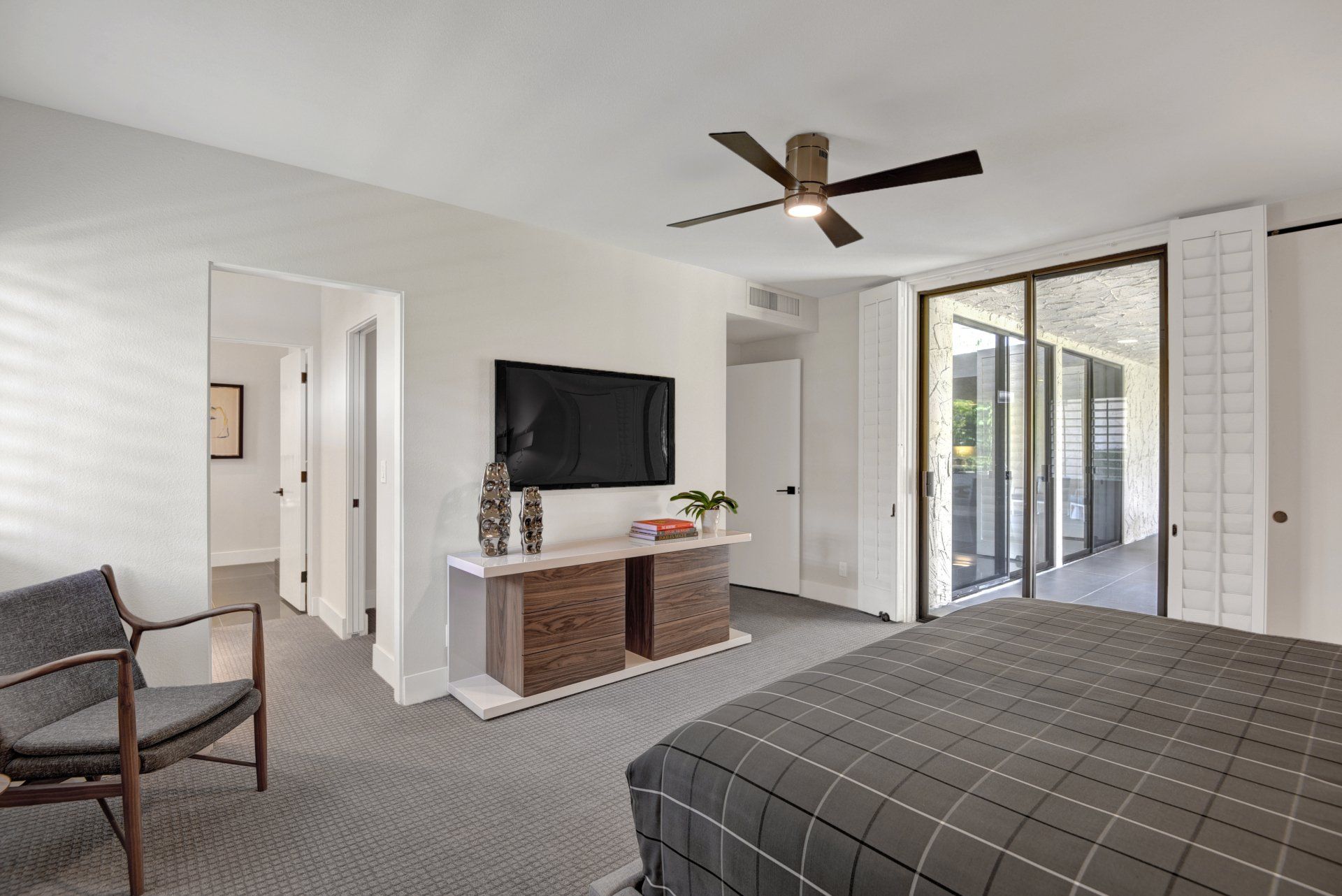 A bedroom with a bed , chair , television and ceiling fan.