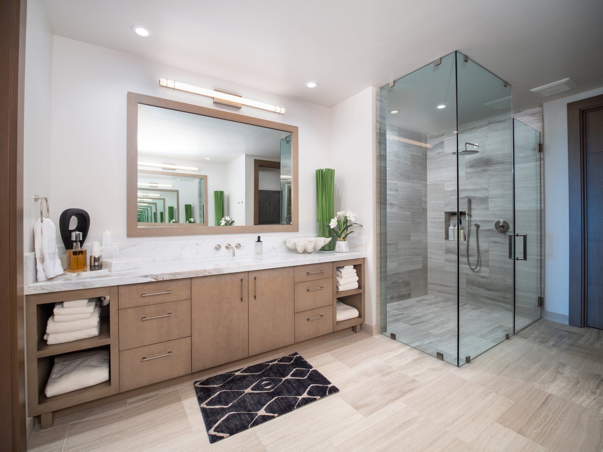 A bathroom with two sinks and a walk in shower.