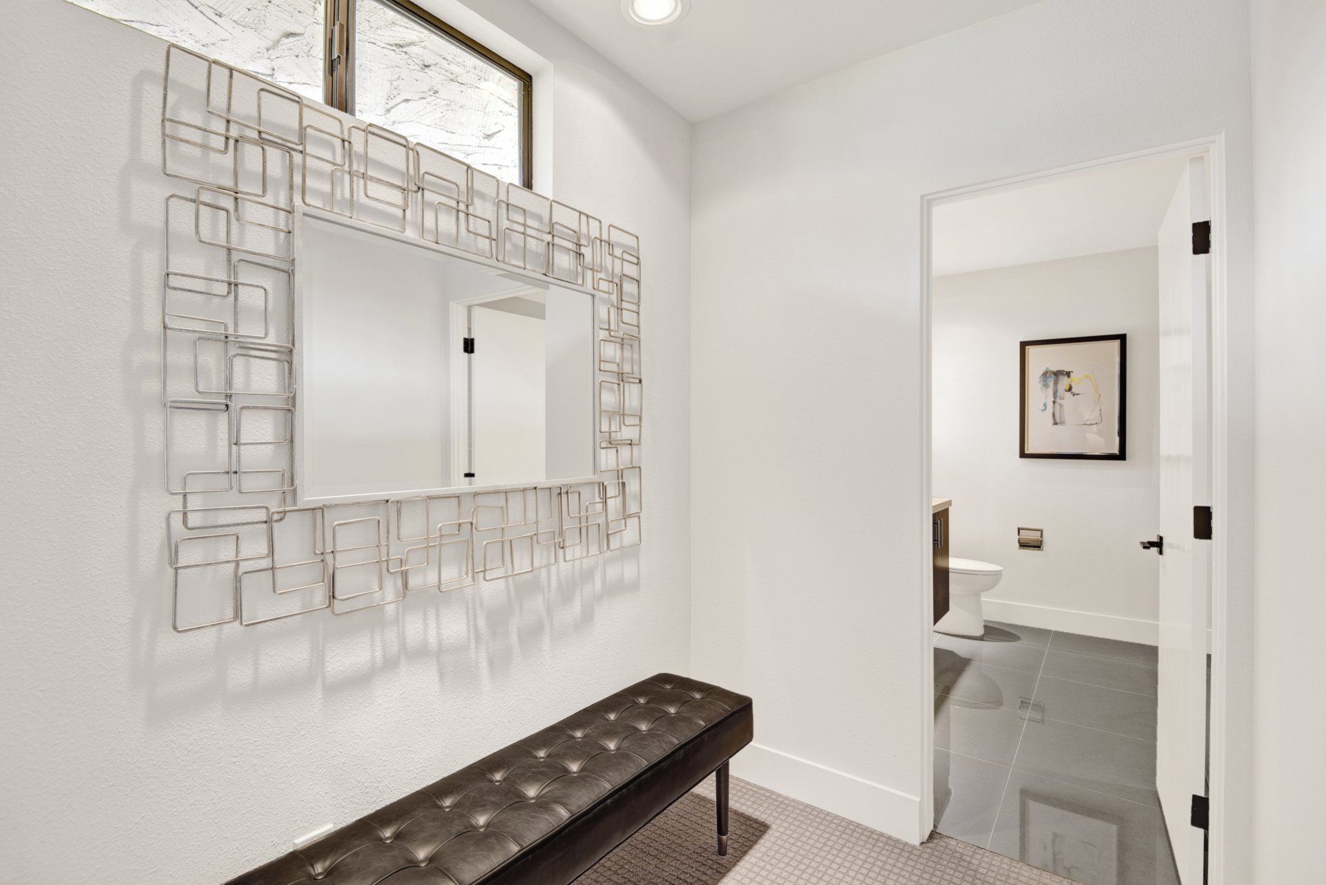 A hallway with a bench and a large mirror on the wall.
