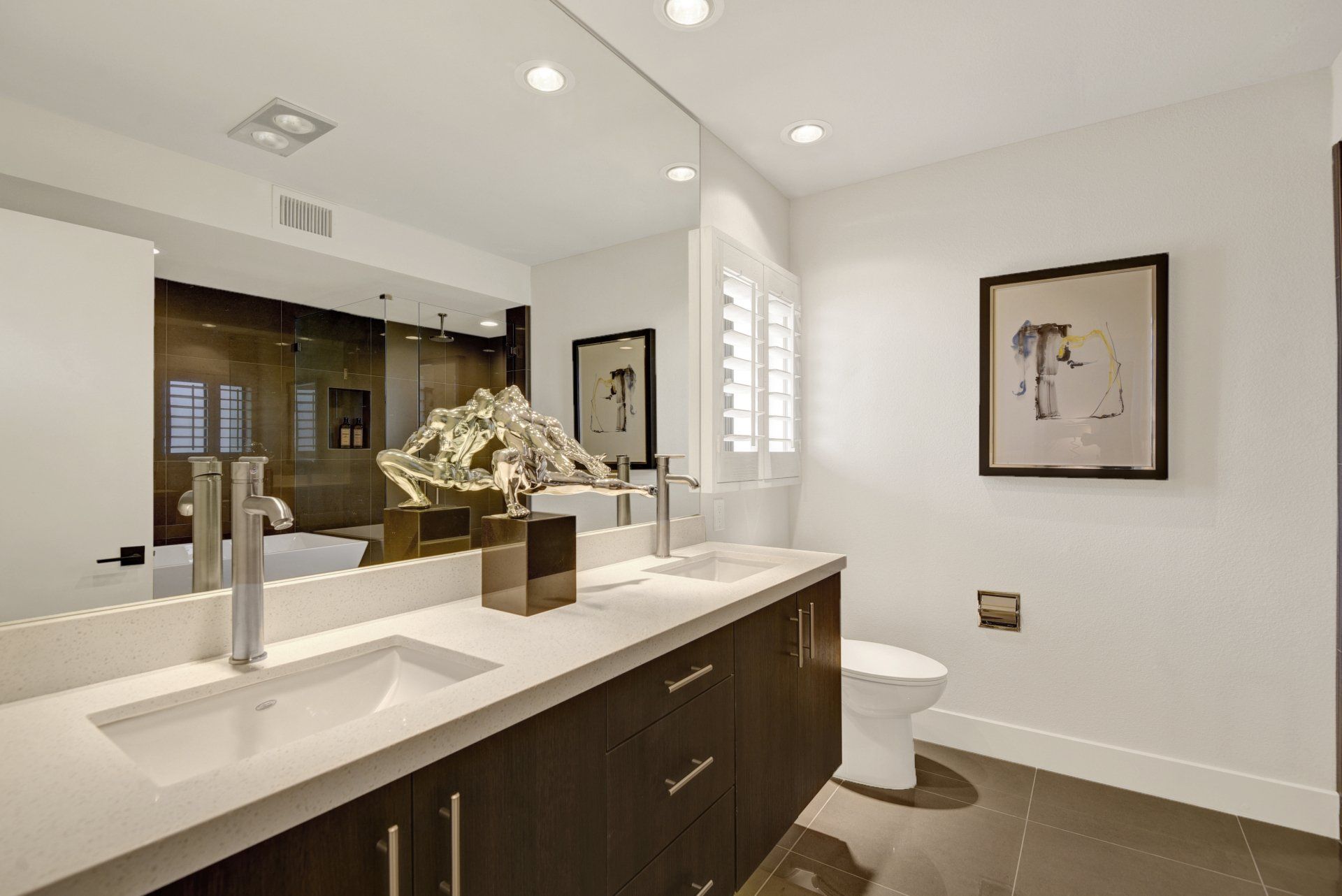 A bathroom with two sinks , a toilet and a large mirror.