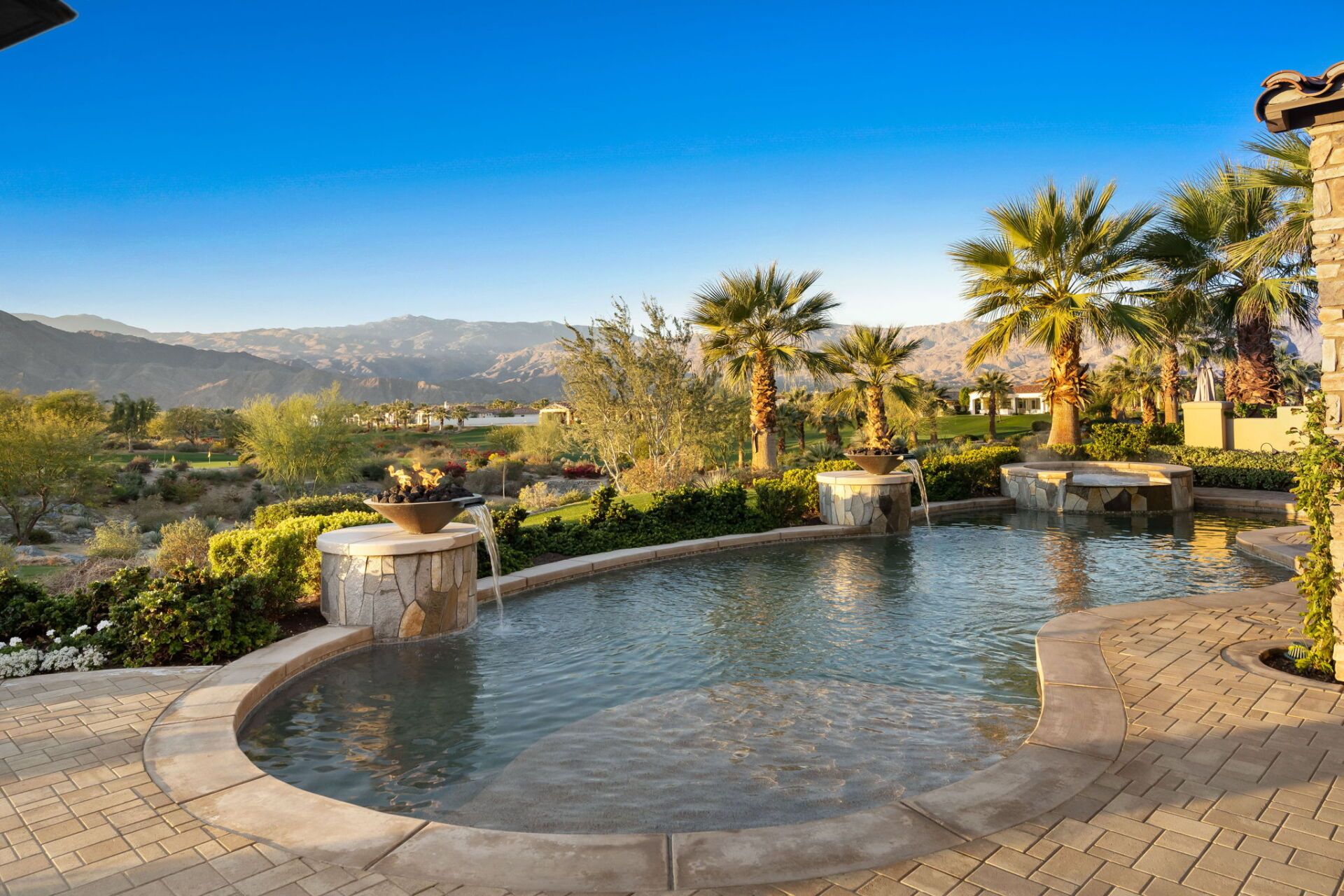 A large swimming pool surrounded by palm trees and mountains.