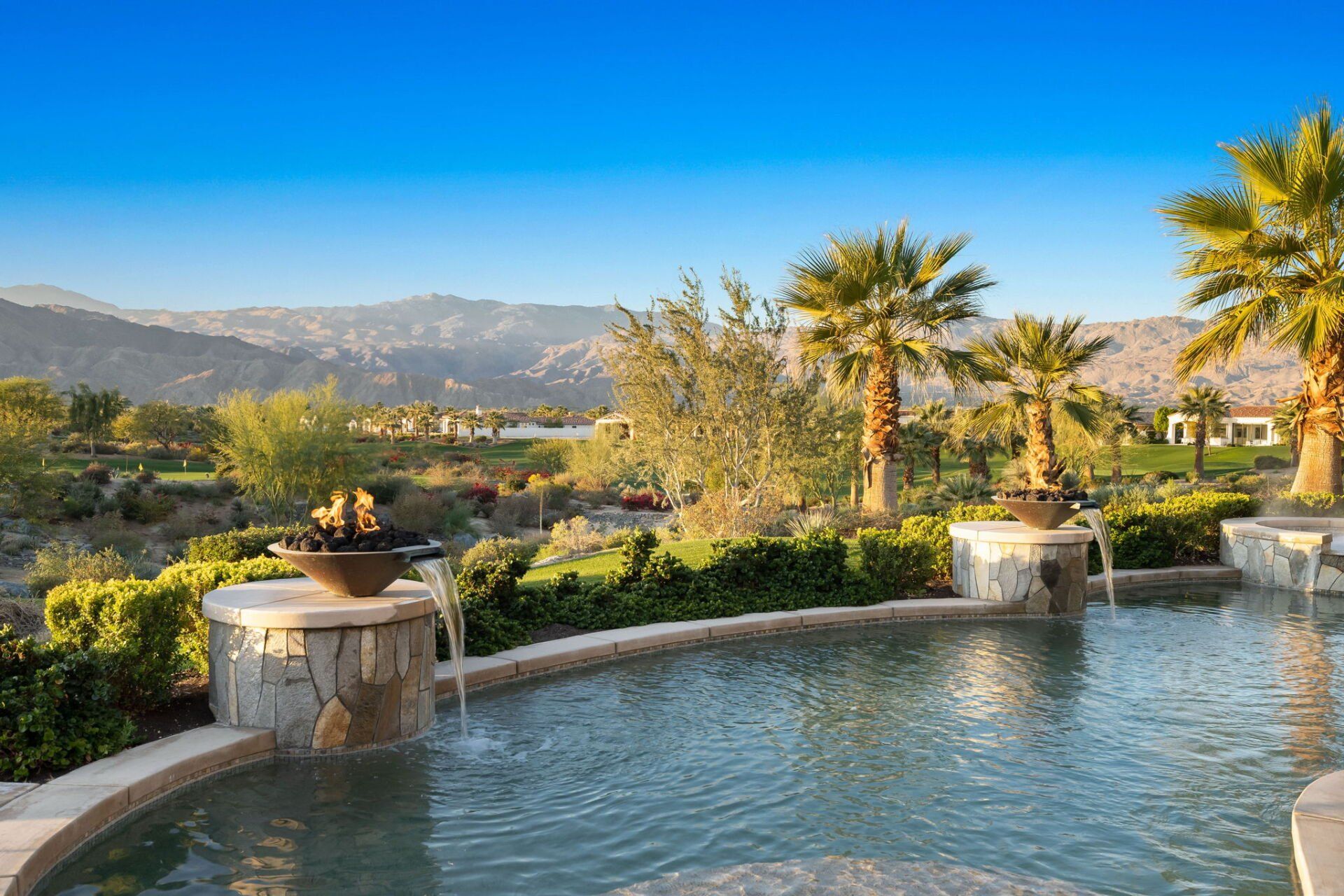 A large swimming pool surrounded by palm trees and mountains