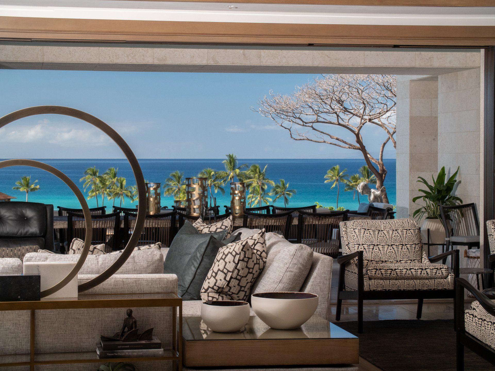 A living room with a couch and chairs and a view of the ocean.