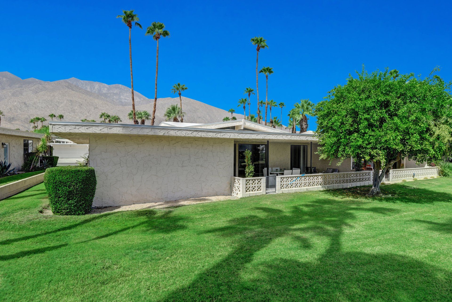 A house with a large lawn in front of it and mountains in the background.