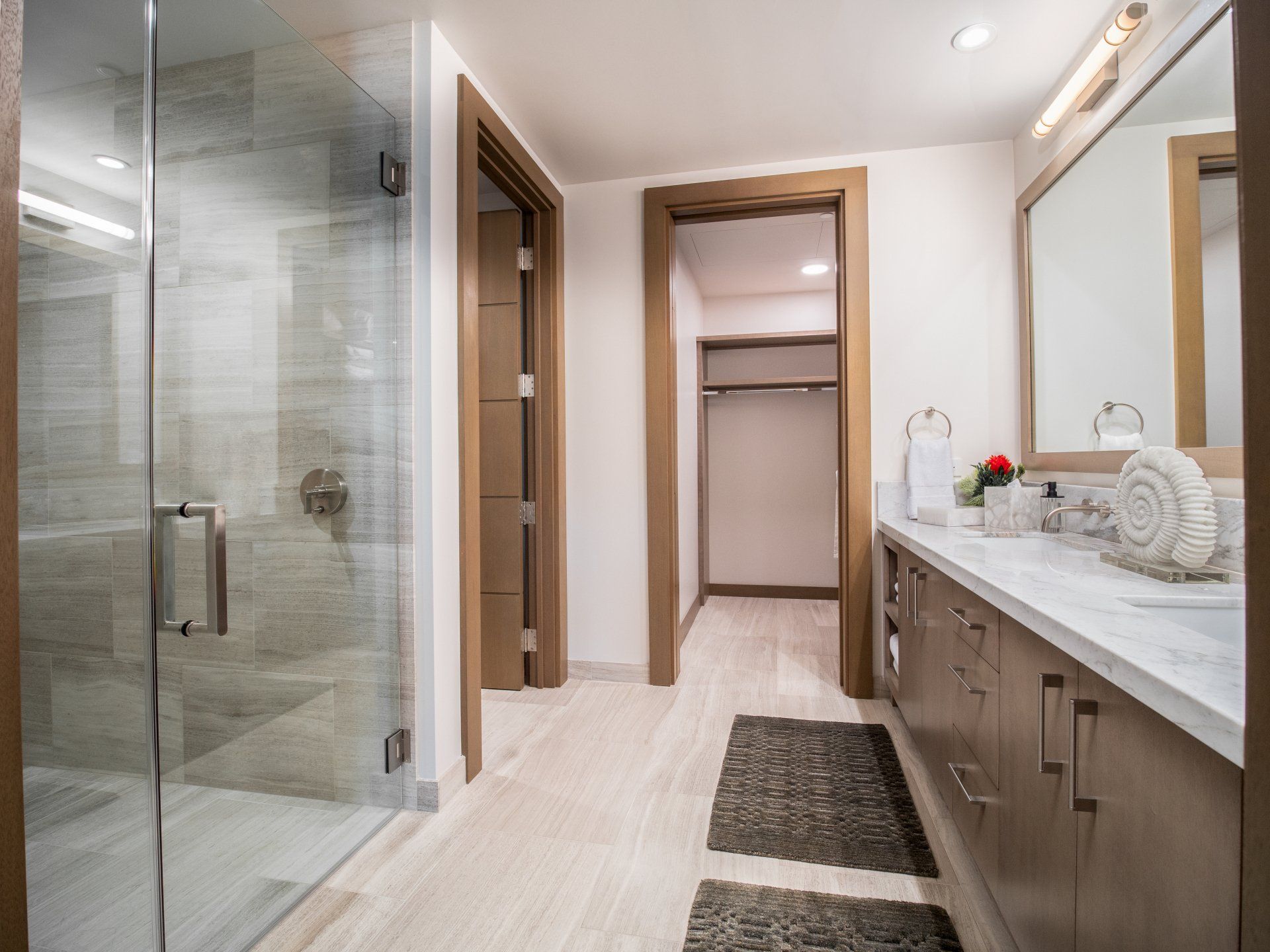 A bathroom with two sinks , a walk in shower and a mirror.