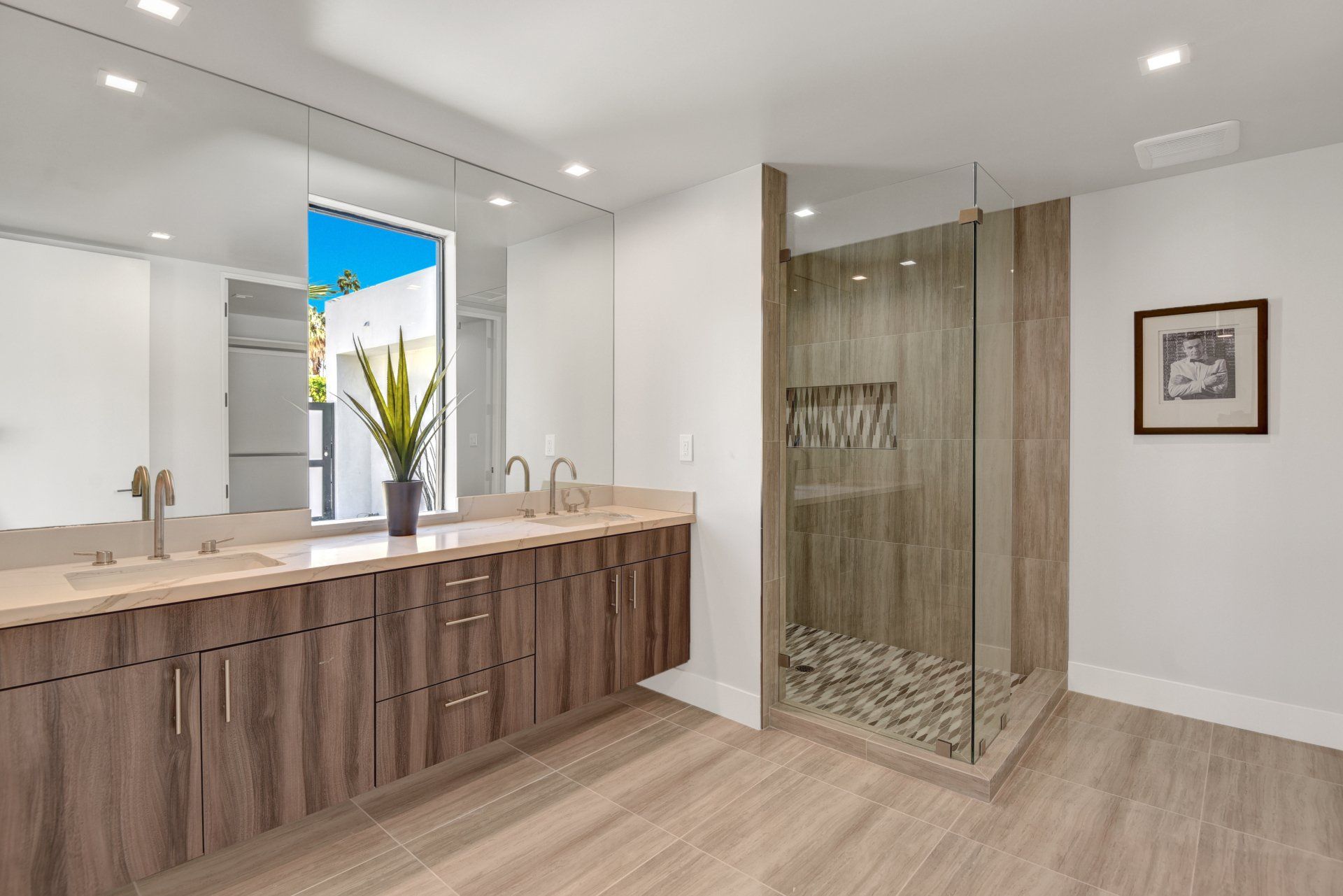 A bathroom with two sinks and a walk in shower.