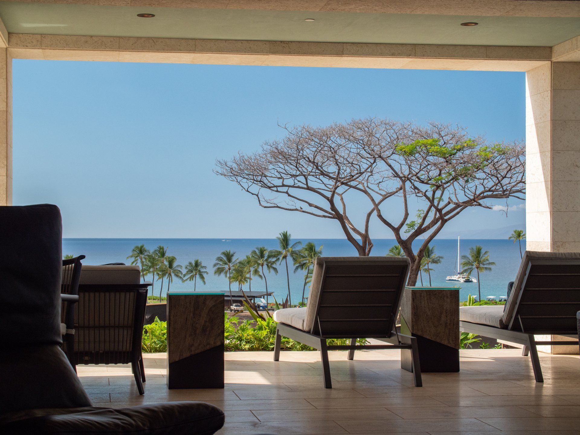 A view of the ocean from a balcony with chairs and tables.