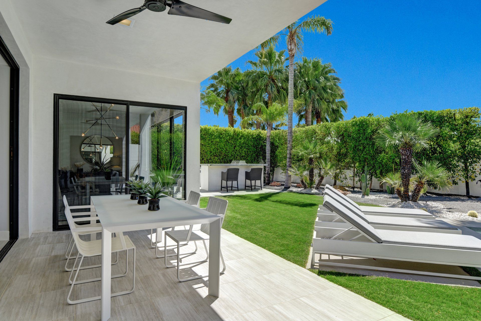A patio with a table and chairs and a ceiling fan.