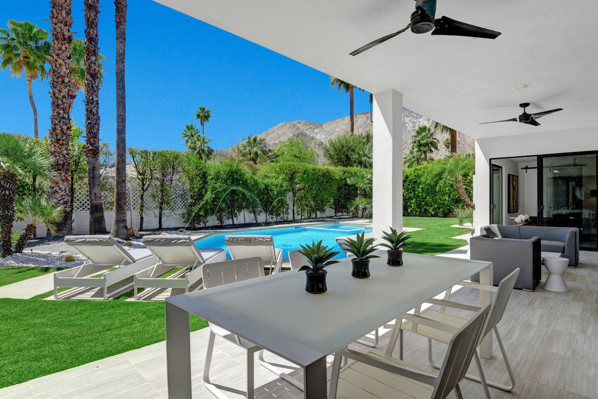 A patio with a table and chairs and a swimming pool in the background