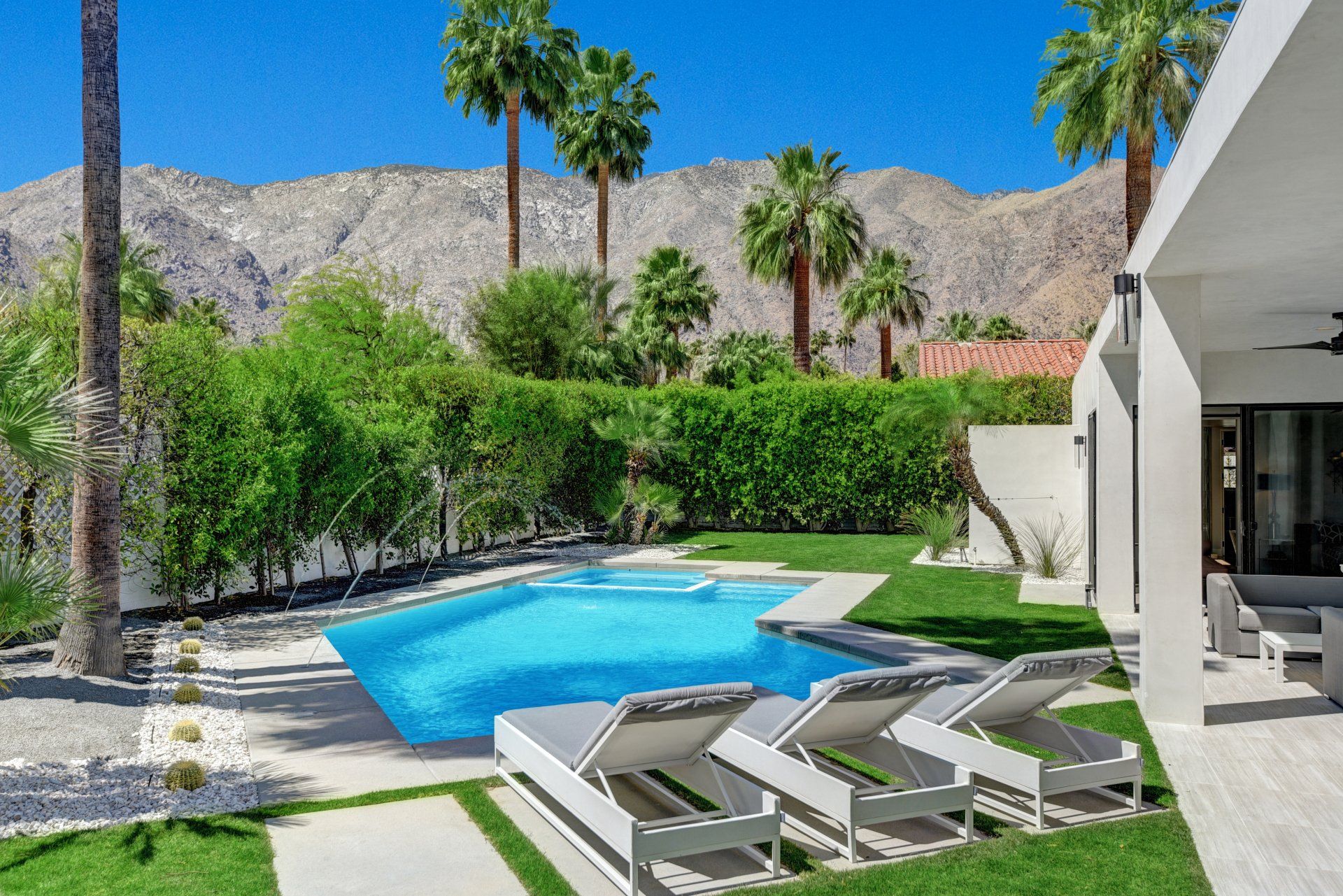 There is a large swimming pool in the backyard of a house.