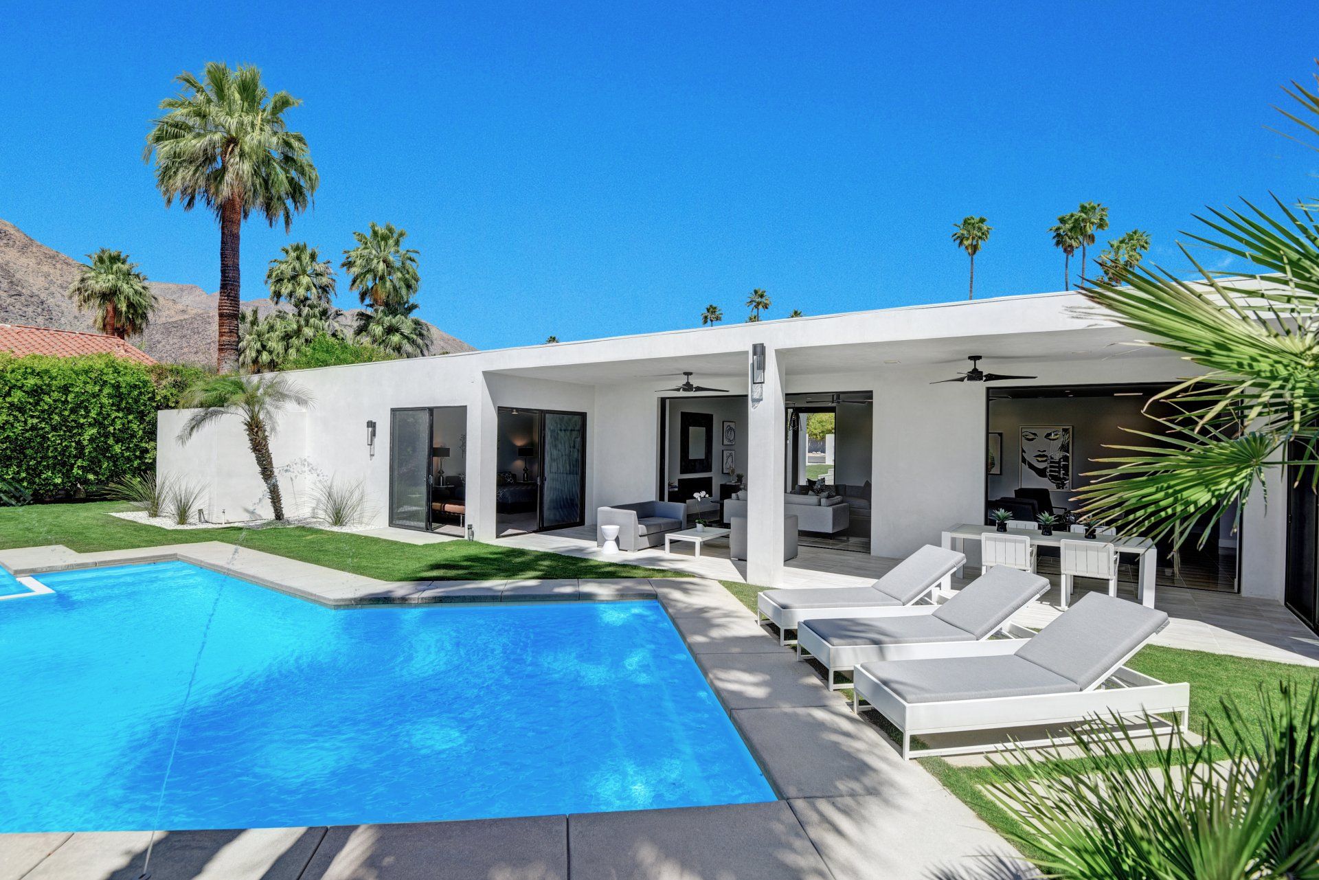 A white house with a large swimming pool in front of it.