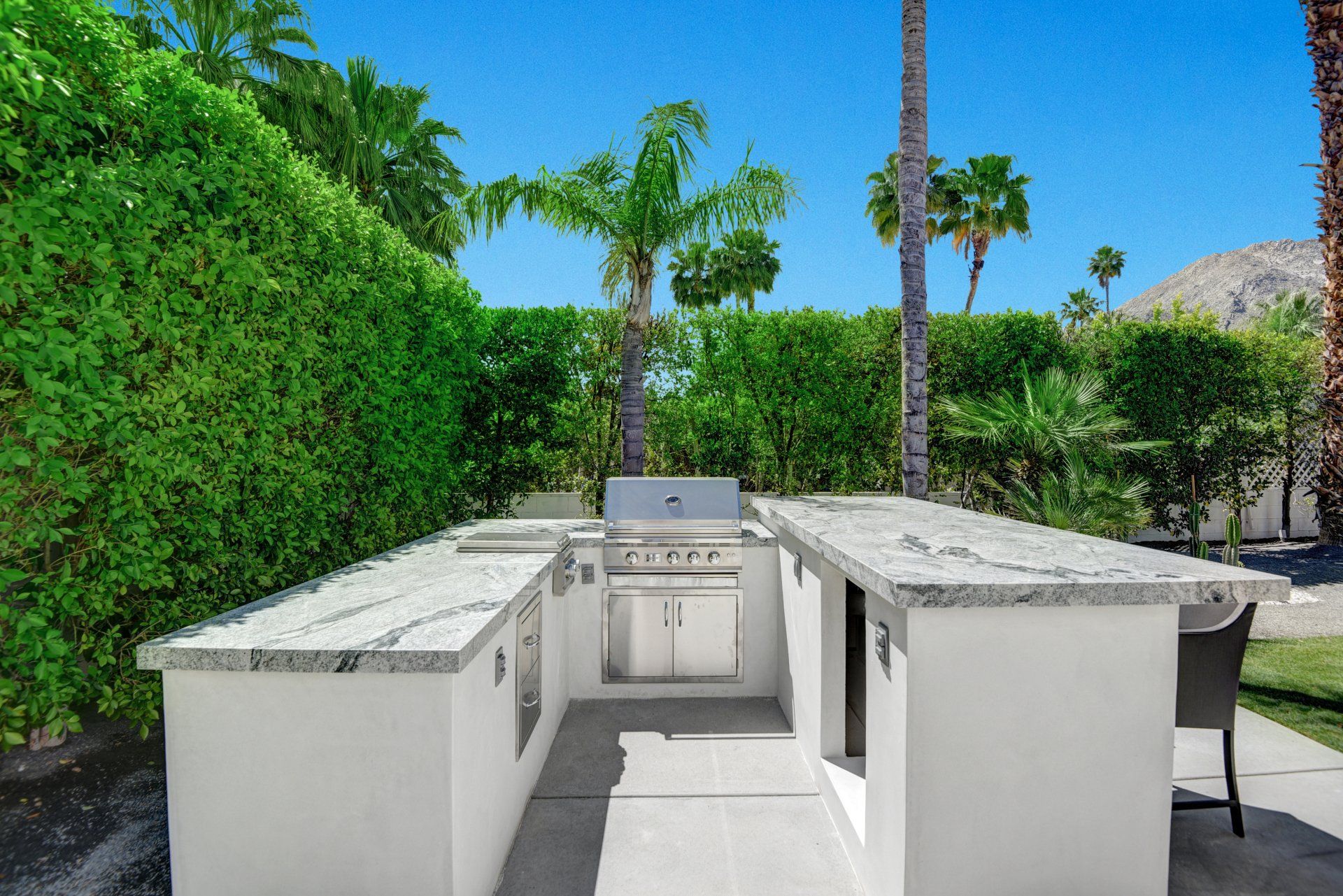 A large outdoor kitchen with a grill and a table.
