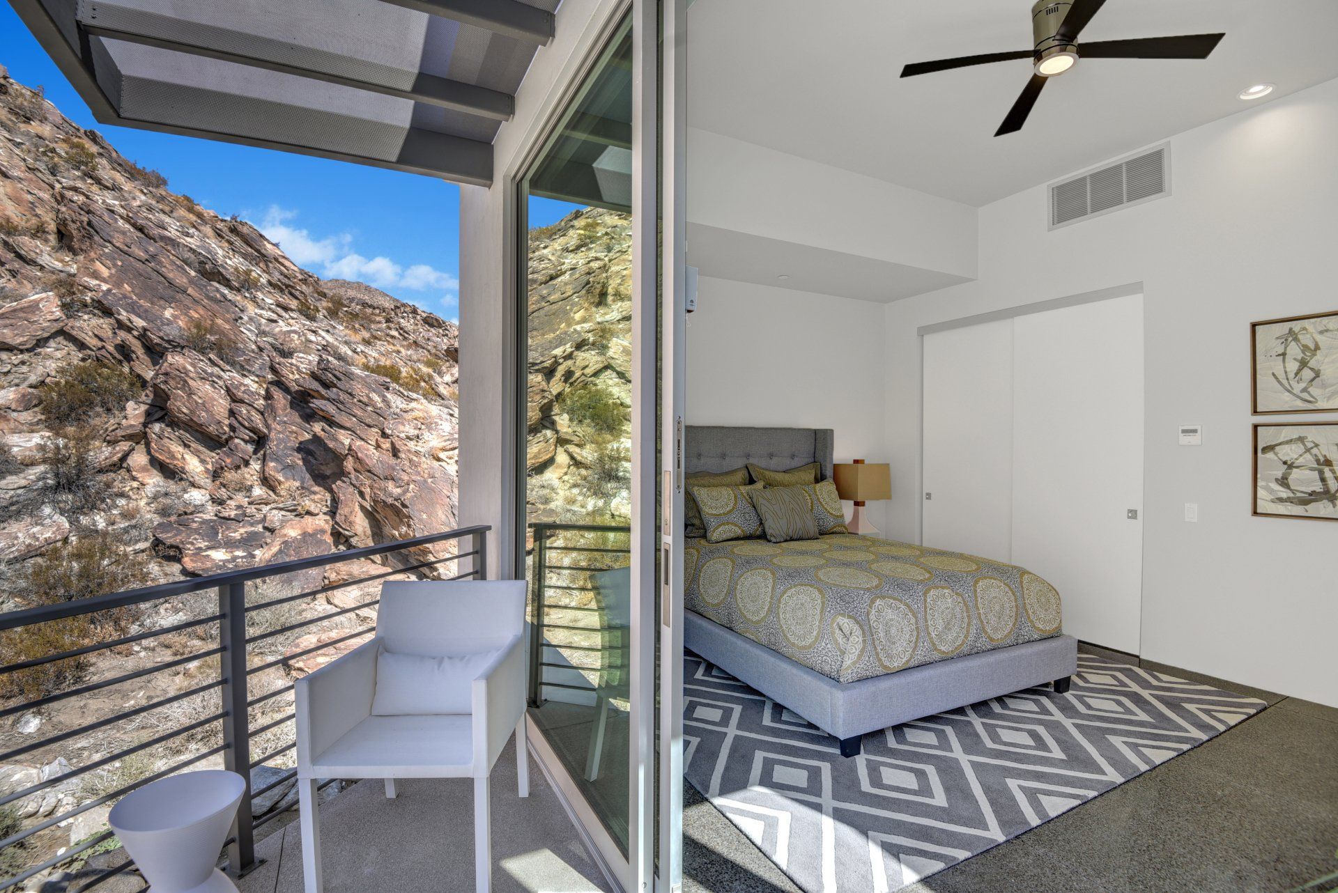 A bedroom with a bed and a balcony with a view of a mountain.