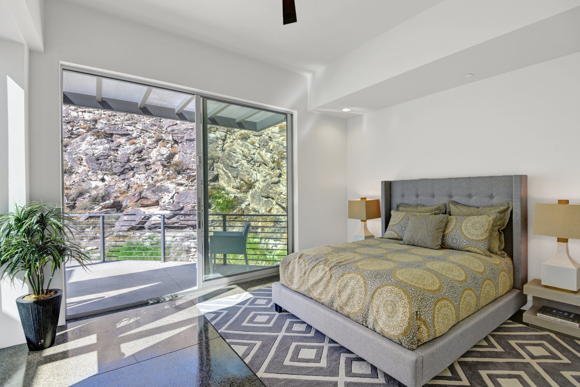 A bedroom with a large bed , sliding glass doors , lamps and a rug.