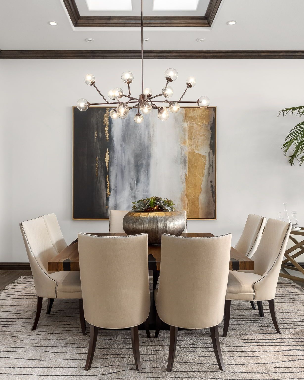 A dining room with a table and chairs and a chandelier hanging from the ceiling.