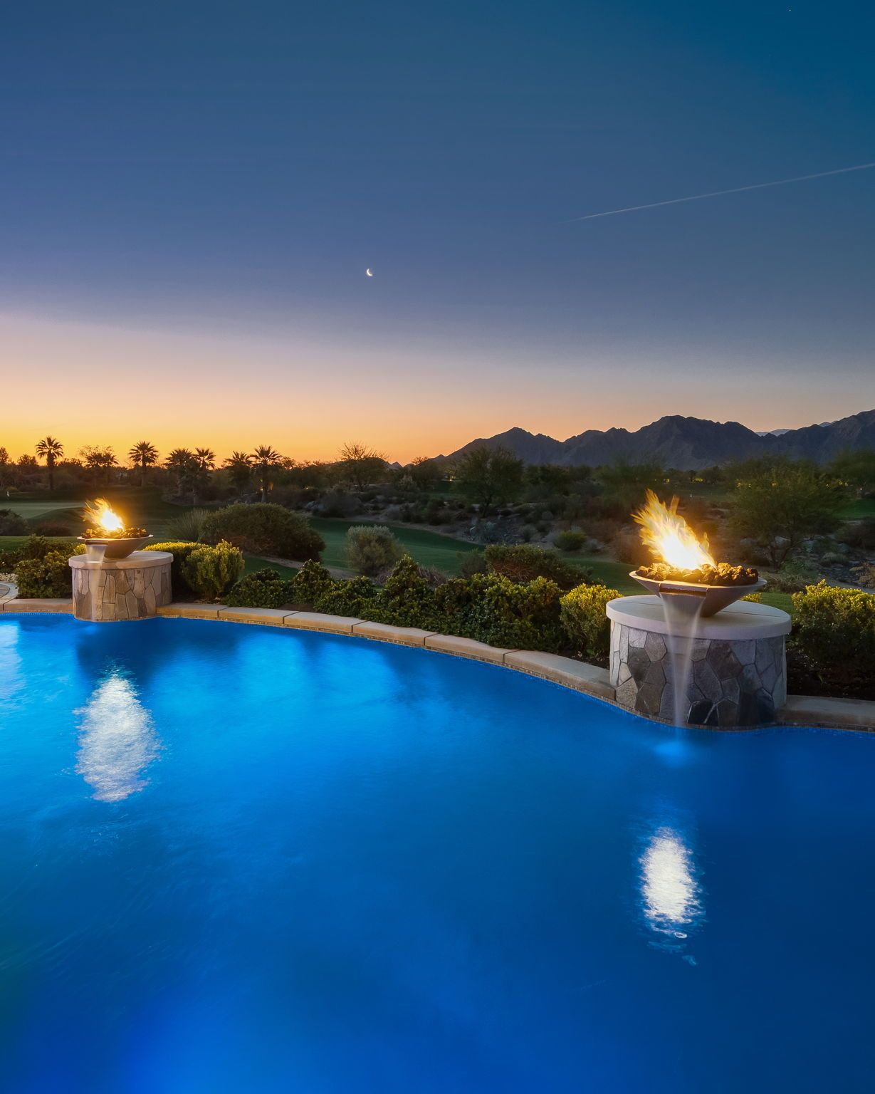 A large swimming pool with a fire pit in the middle of it.