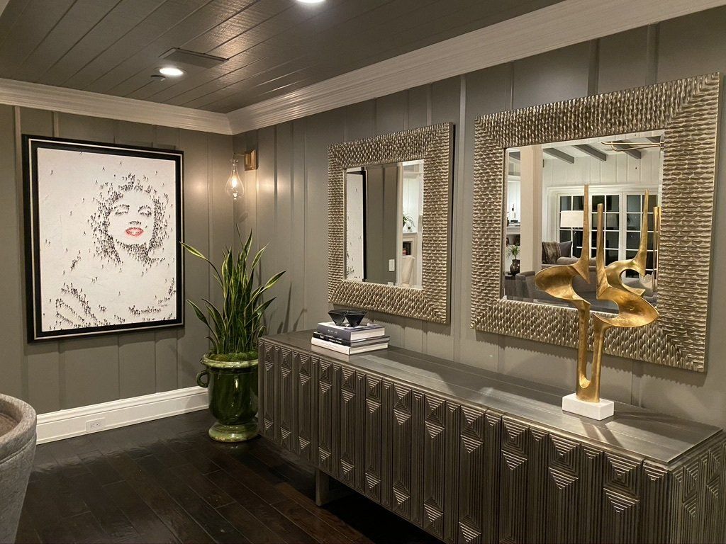 A living room with two mirrors and a painting on the wall