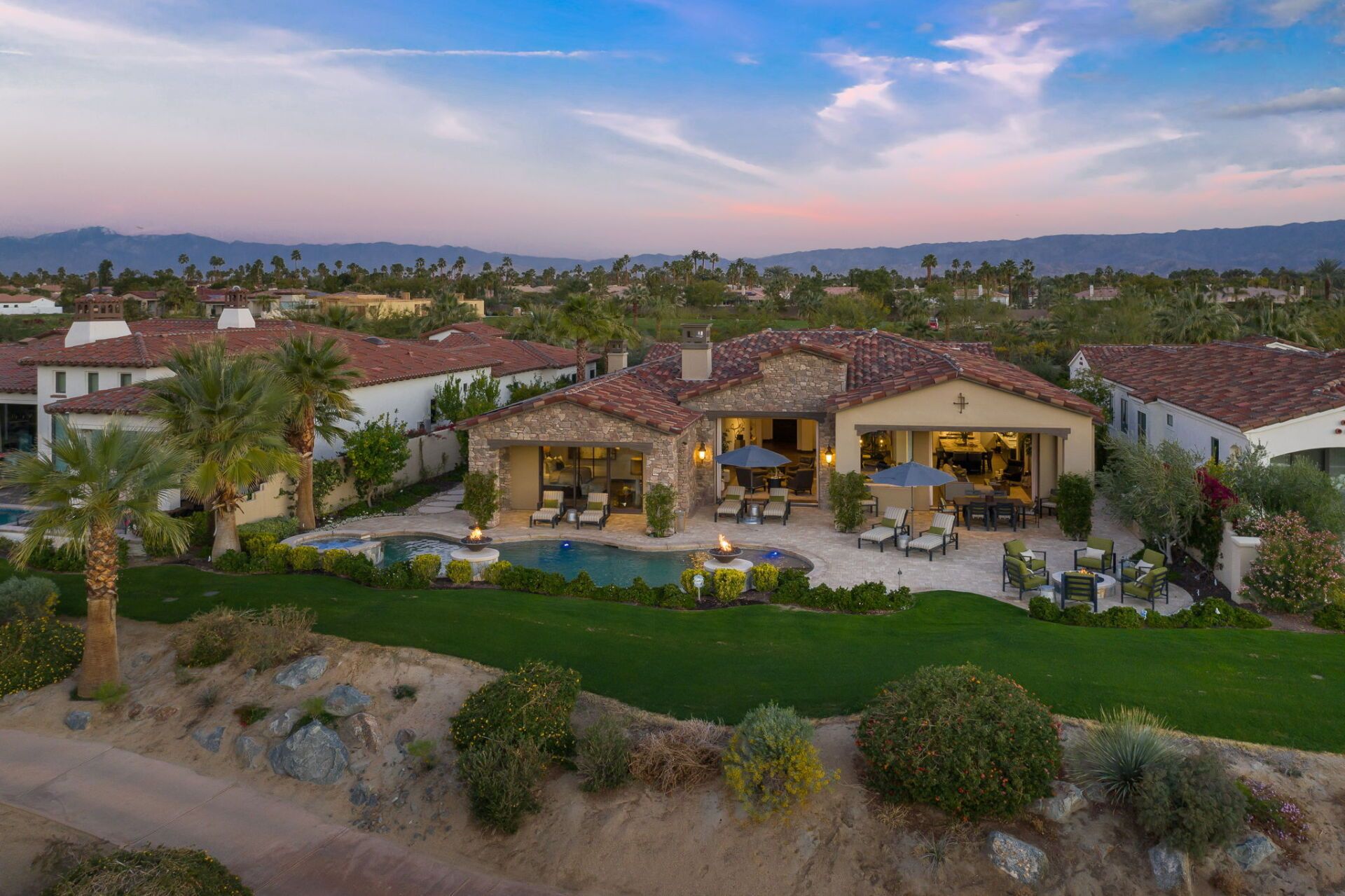 An aerial view of a large house with a pool and palm trees.
