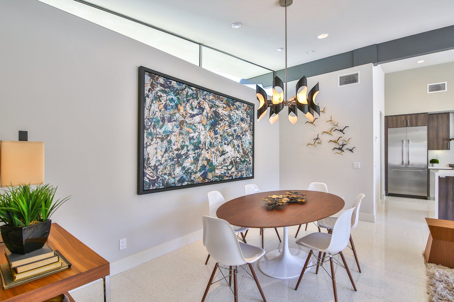 A dining room with a round table and chairs and a large painting on the wall.