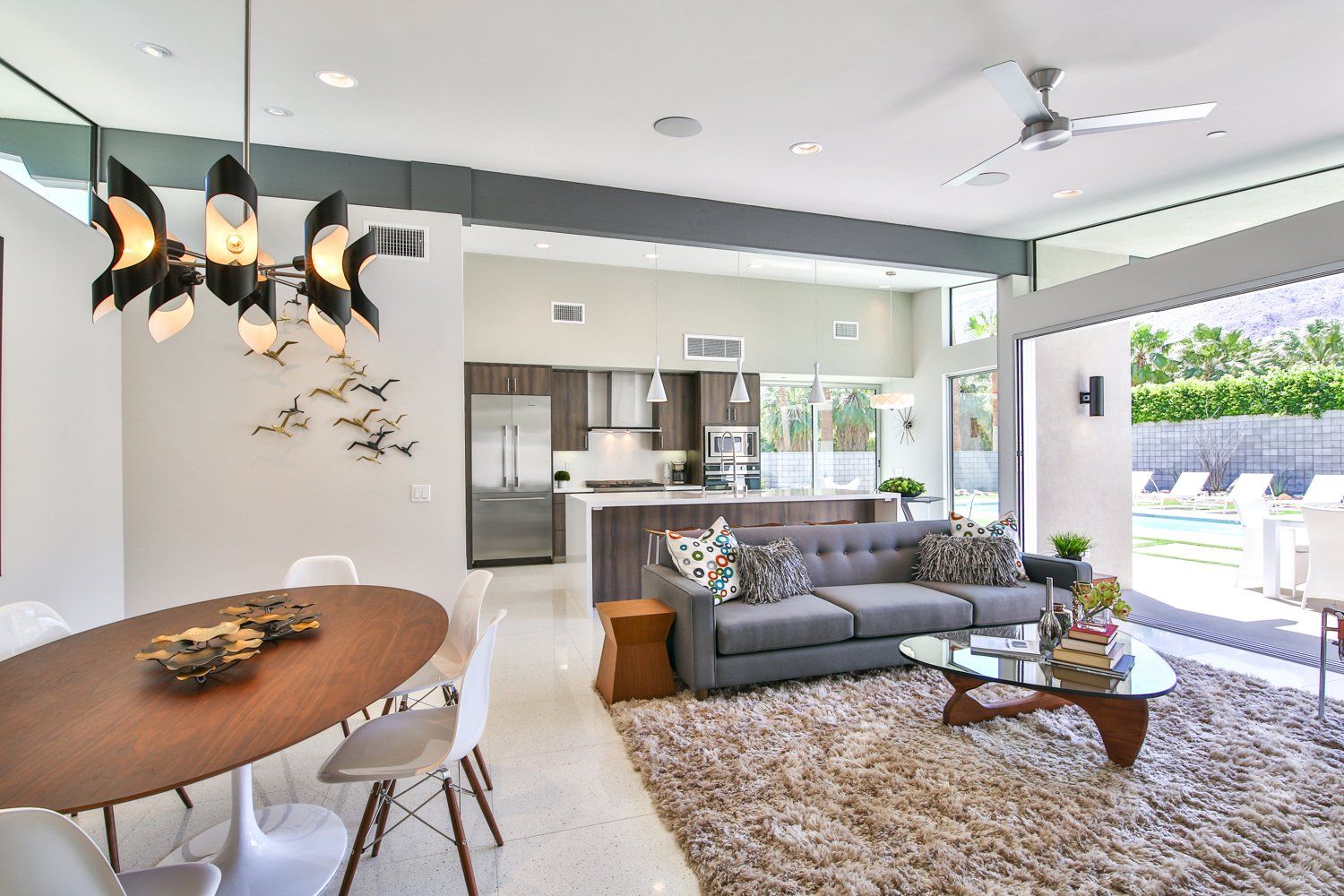 A living room with a couch , table , chairs and a ceiling fan.