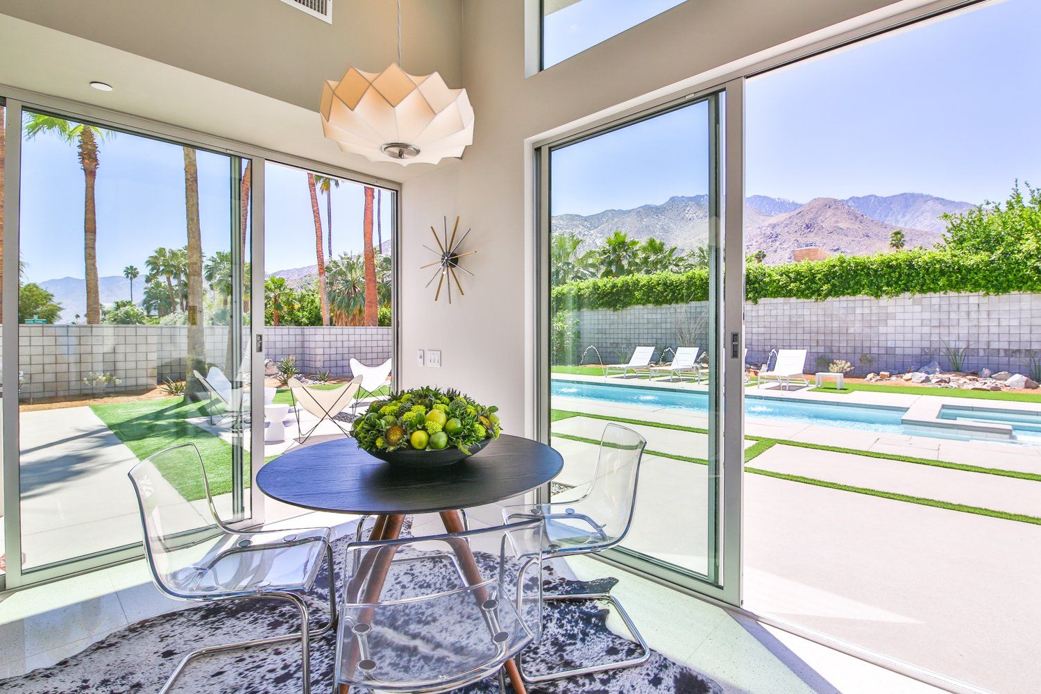A dining room with a table and chairs and a clock on the wall.