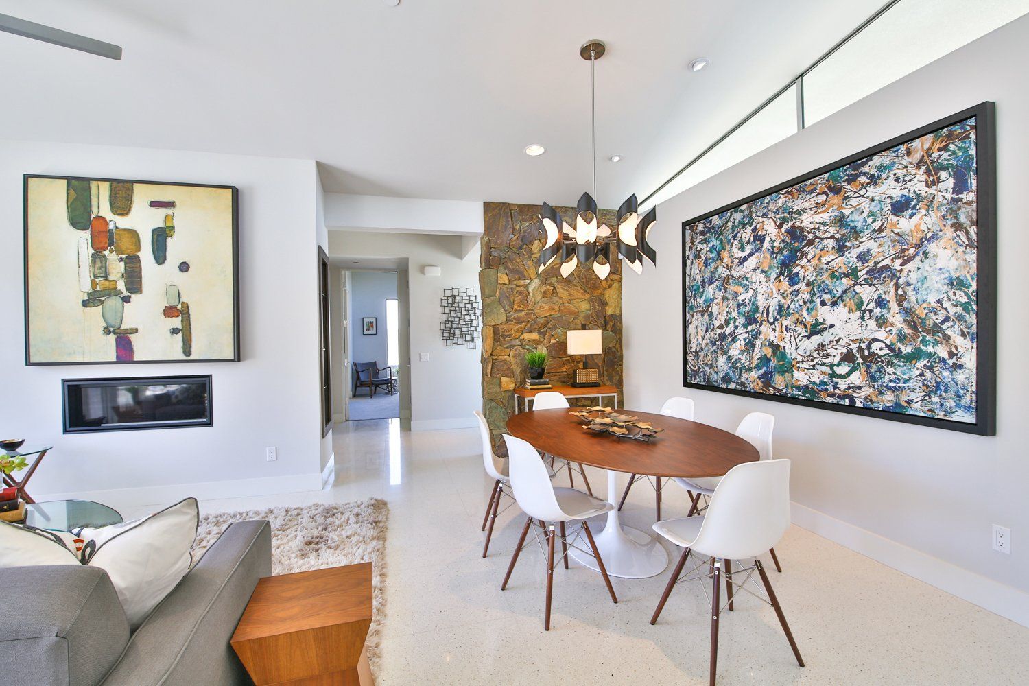 A dining room with a table and chairs and a large painting on the wall.