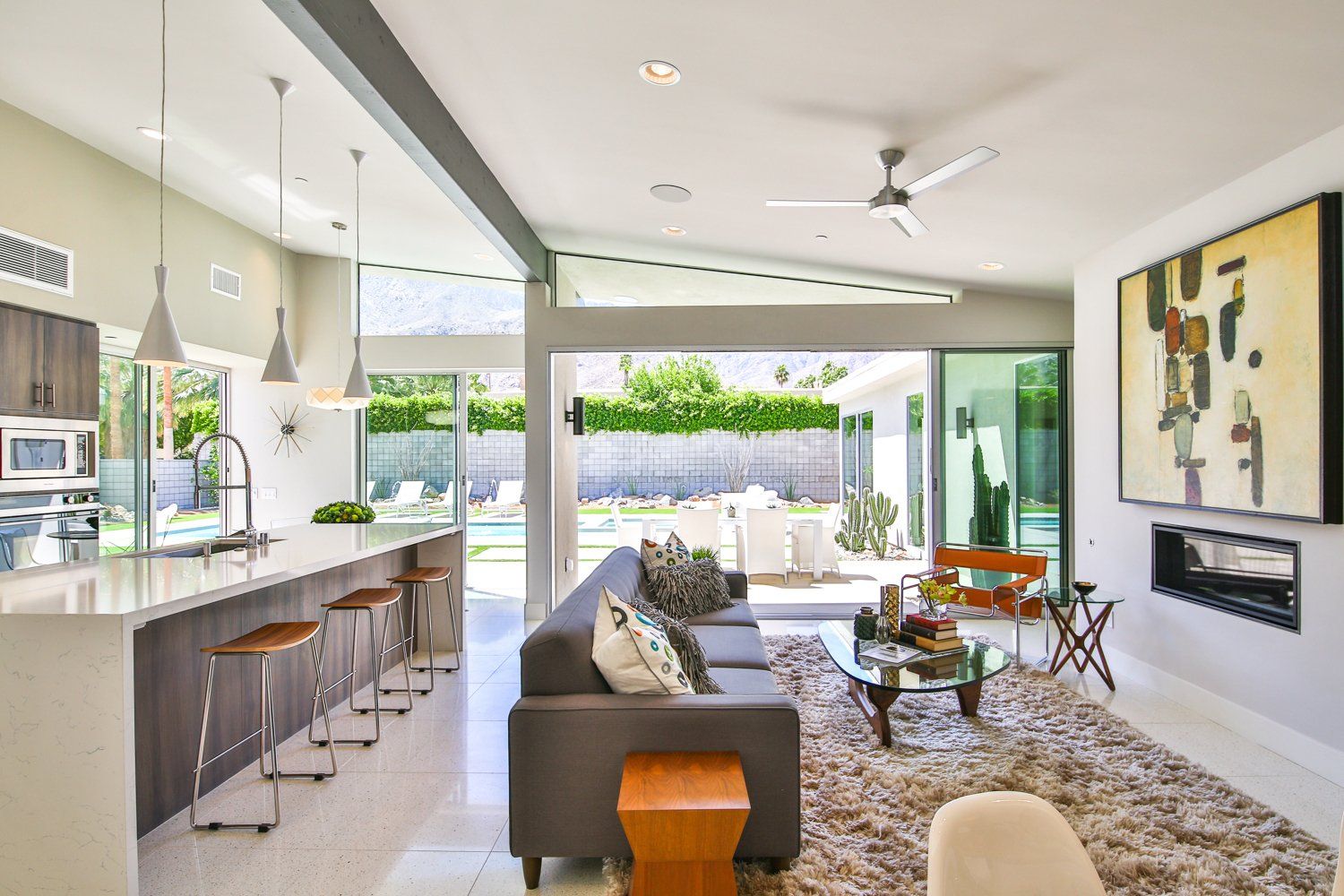 A living room with a couch , table , chairs and a ceiling fan.