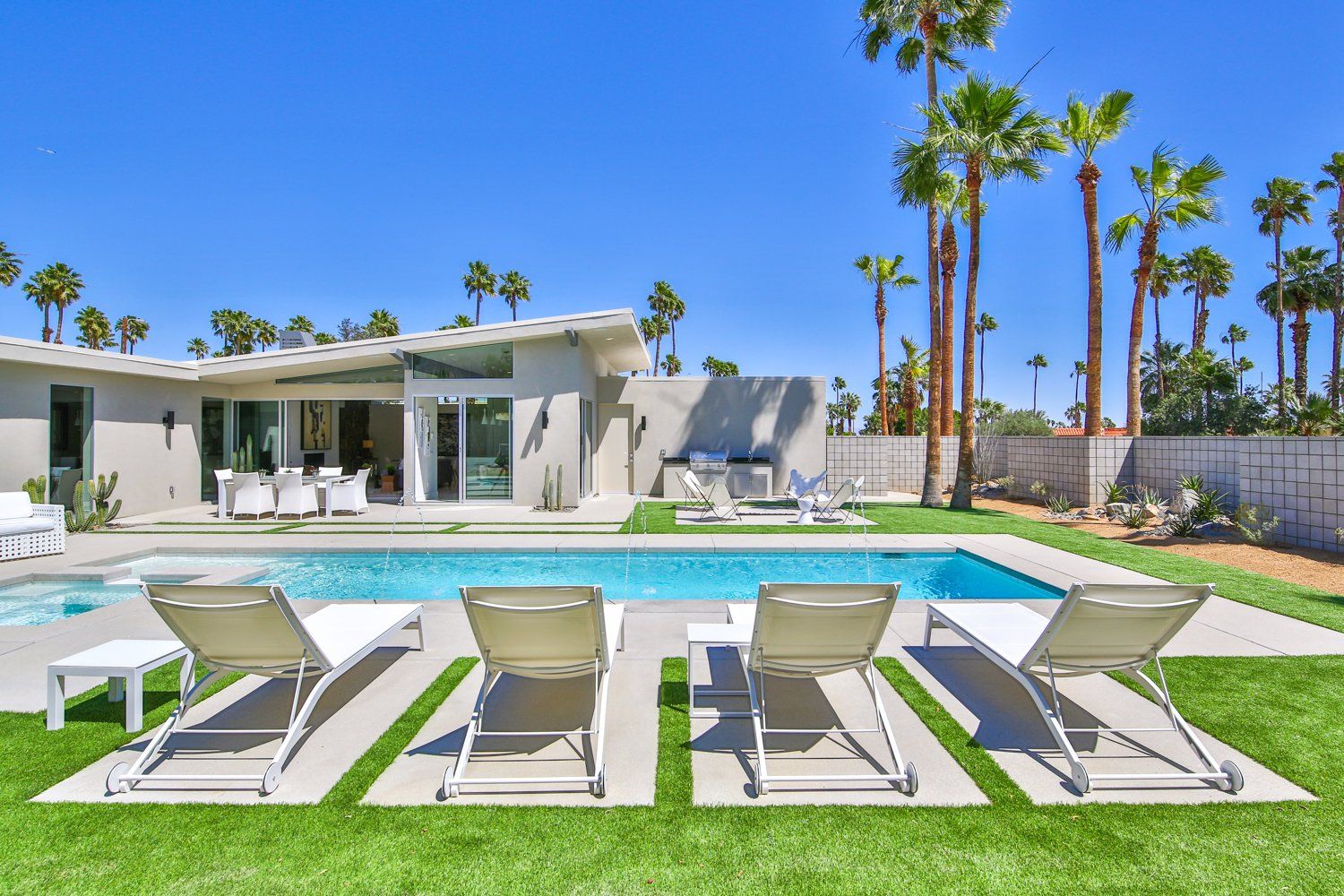 A house with a swimming pool and lawn chairs in front of it.