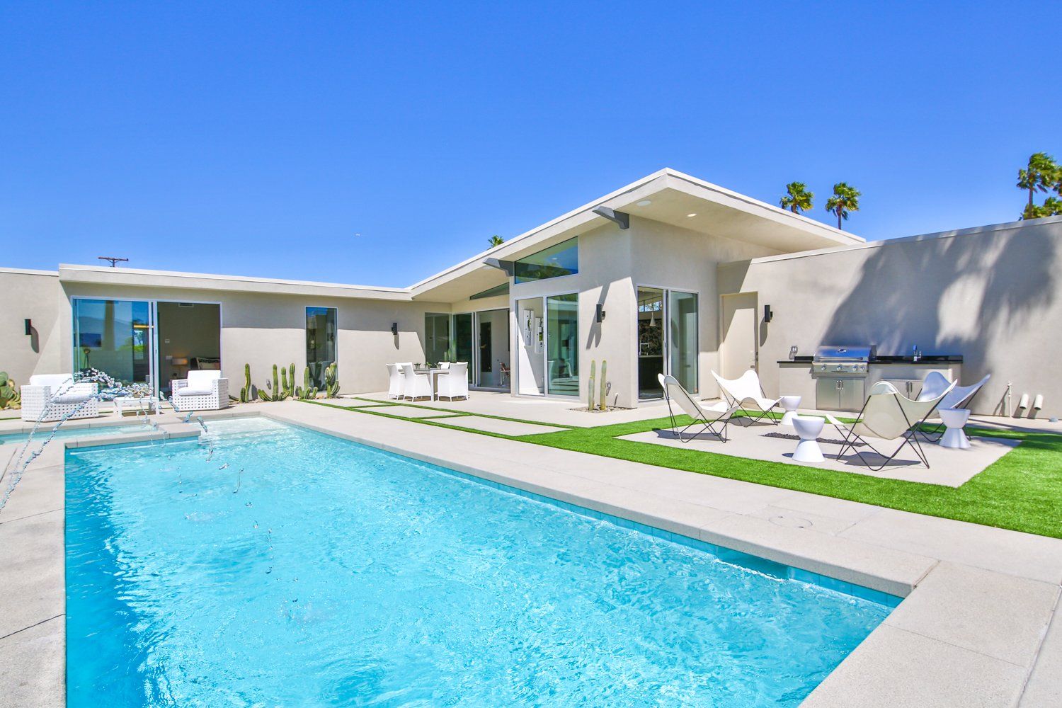 A large white house with a large swimming pool in front of it.