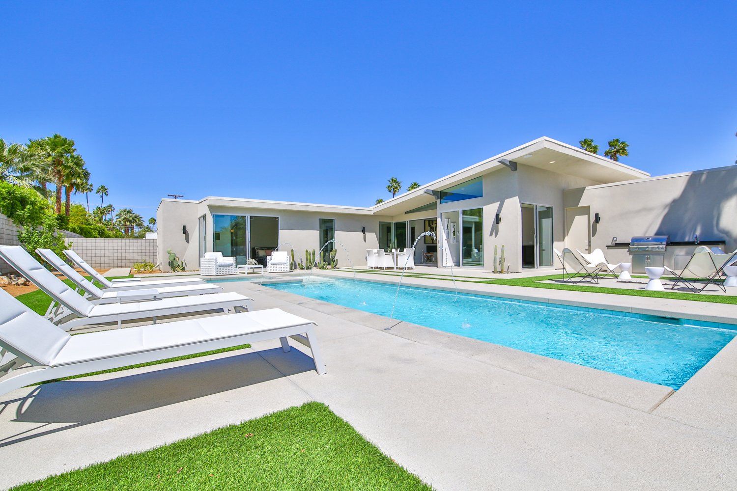 There is a large swimming pool in the backyard of a house.