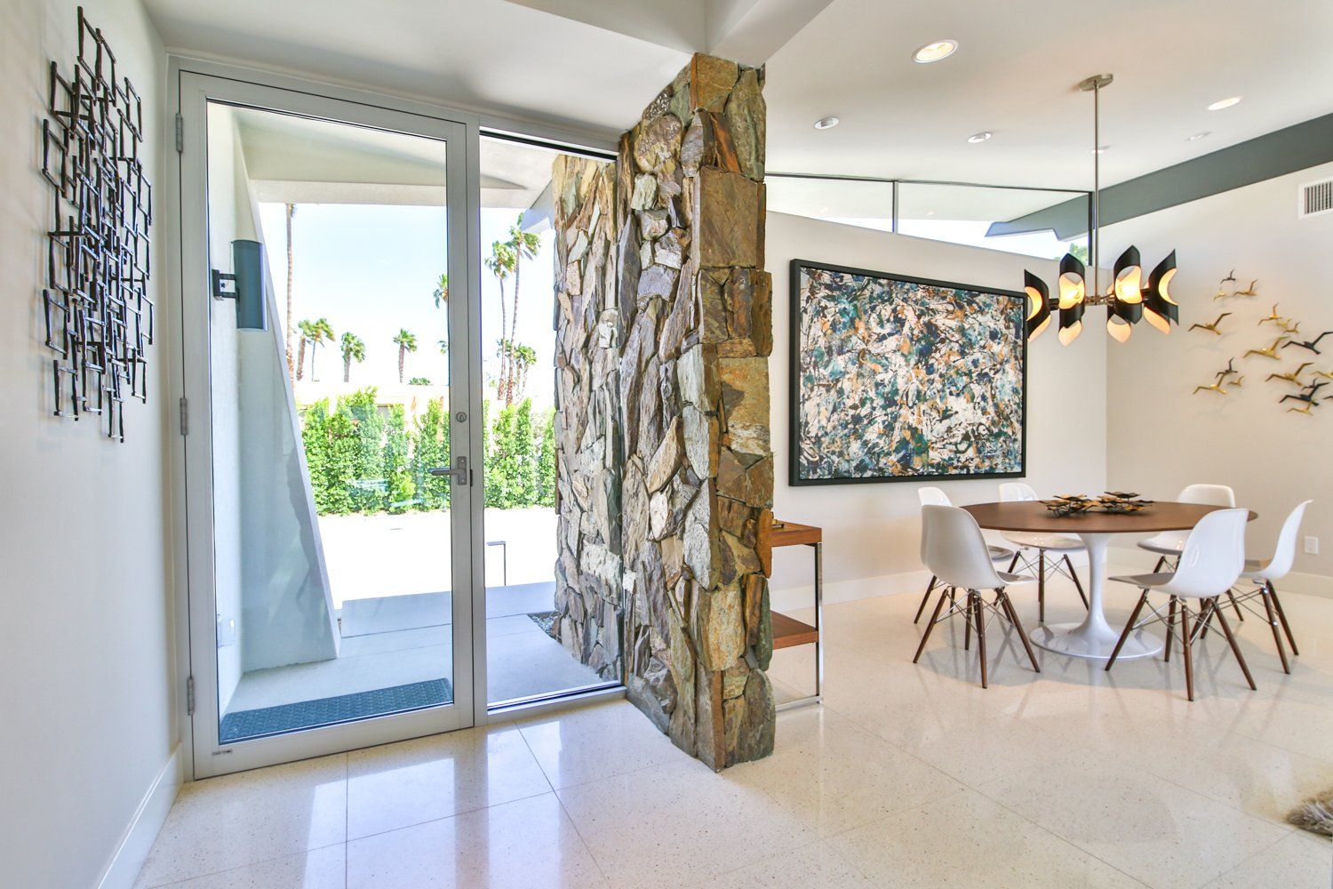 A dining room with a table and chairs and a painting on the wall.