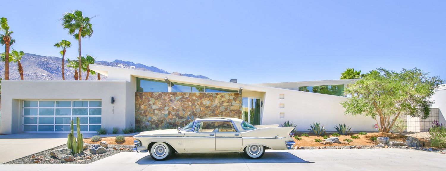 A white car is parked in front of a modern house.