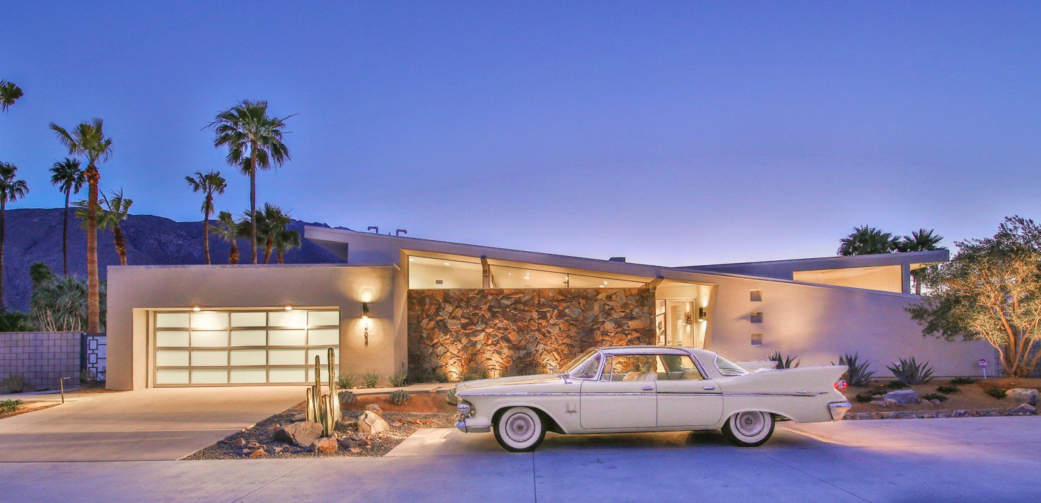 A white car is parked in front of a modern house.