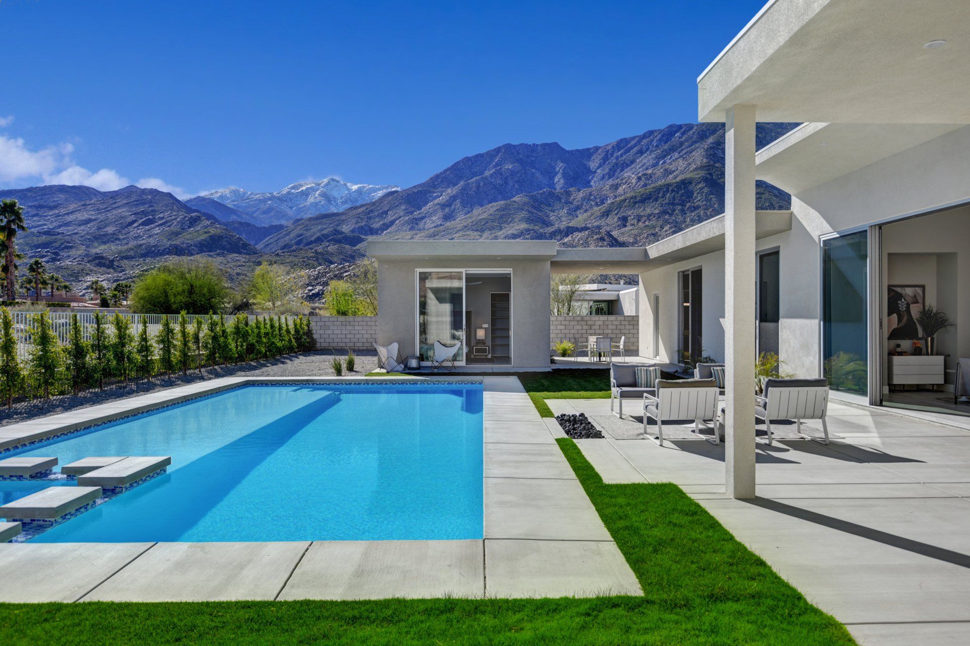A large swimming pool in the backyard of a house with mountains in the background.