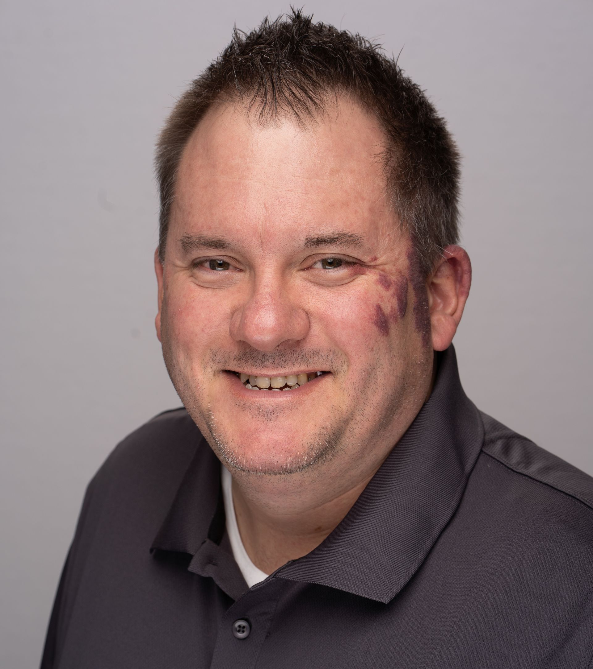 A man with a tattoo on his face is smiling for the camera.