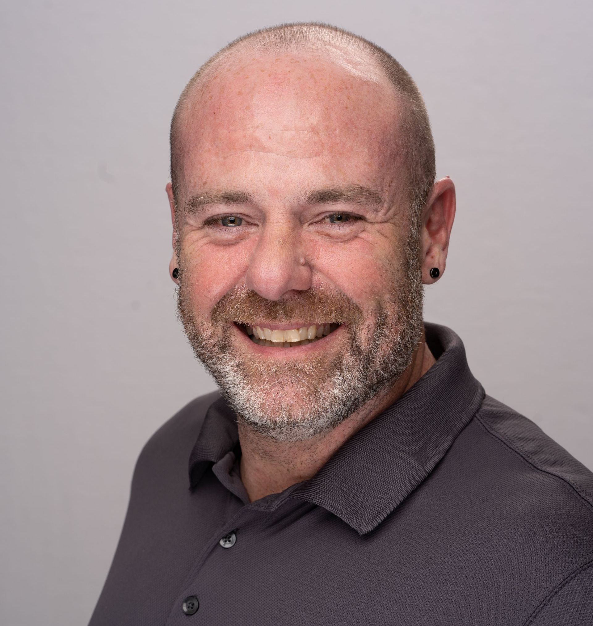 A man with a beard and earrings is smiling for the camera.